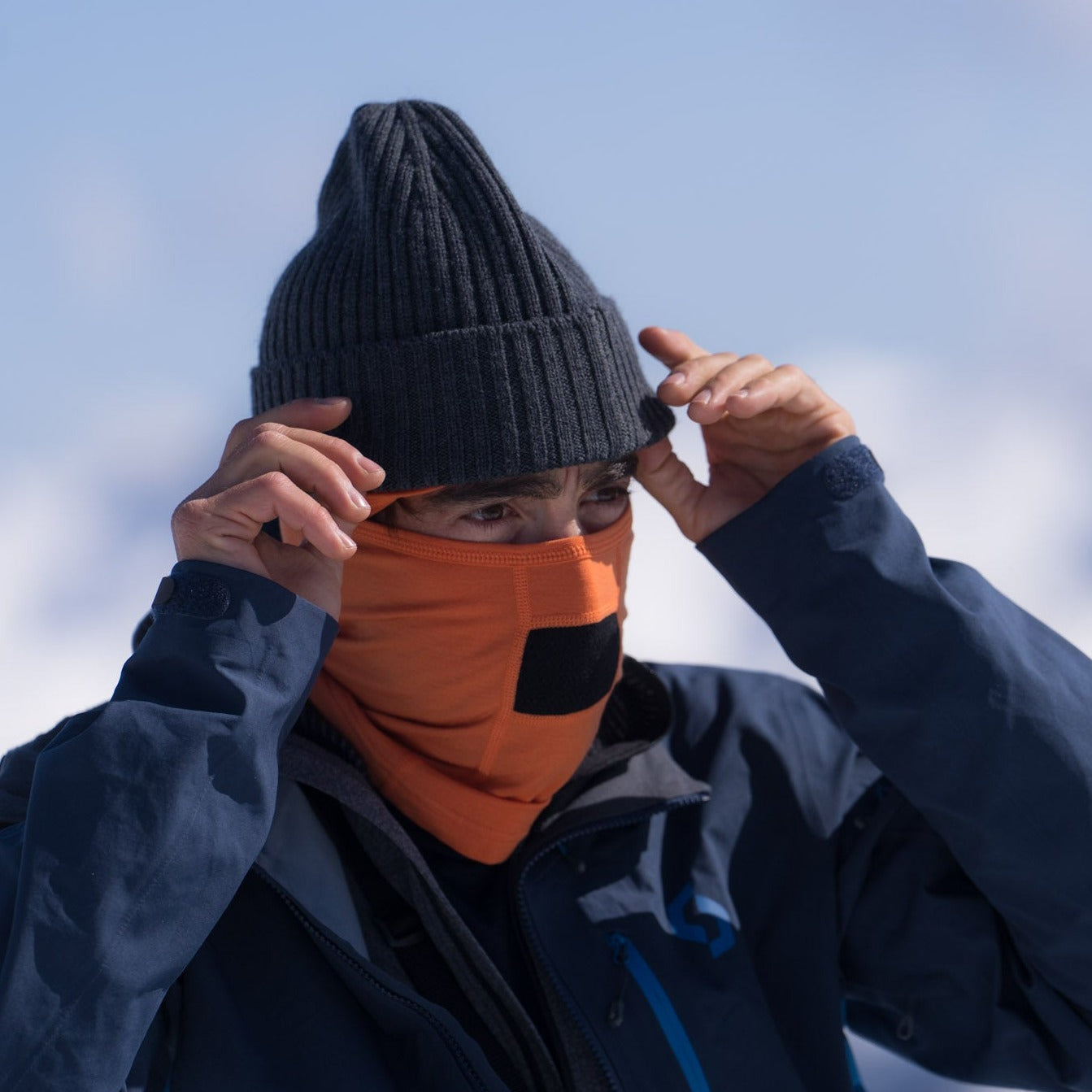 a man wearing a Harvest orange Merino Wool Balaclava and a Ridge beanie