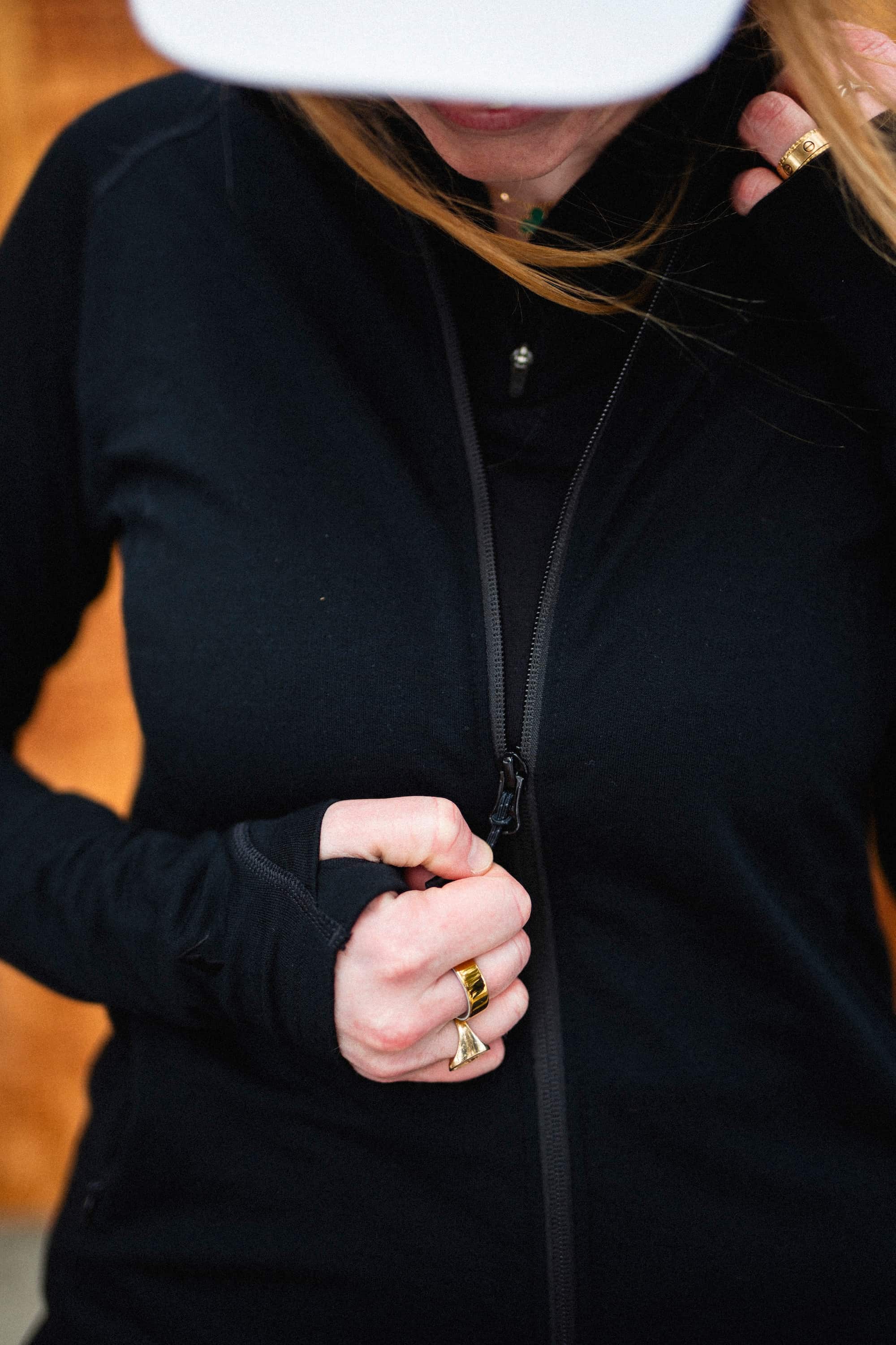a woman zips up a Hyde Merino Hoodie