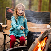 a girl roasts a marshmallow wearing a Ridge Hyde Kids Merino Hoodie