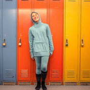 a girl wearing a Ridge Kids' Hyde Merino Hoodie and base layers in a ski locker room