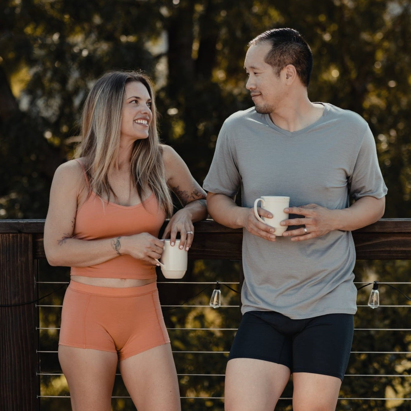 a woman and a man wearing Ridge underwear and tees drink coffee on the porch