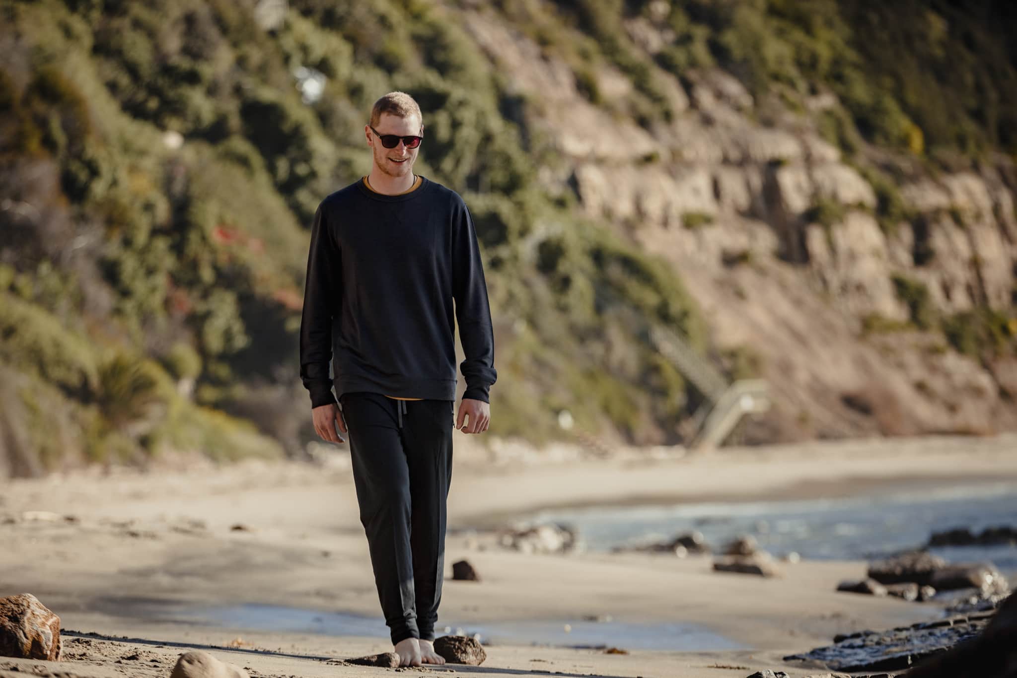 a man walking along the beach in Malibu in Ridge clothing