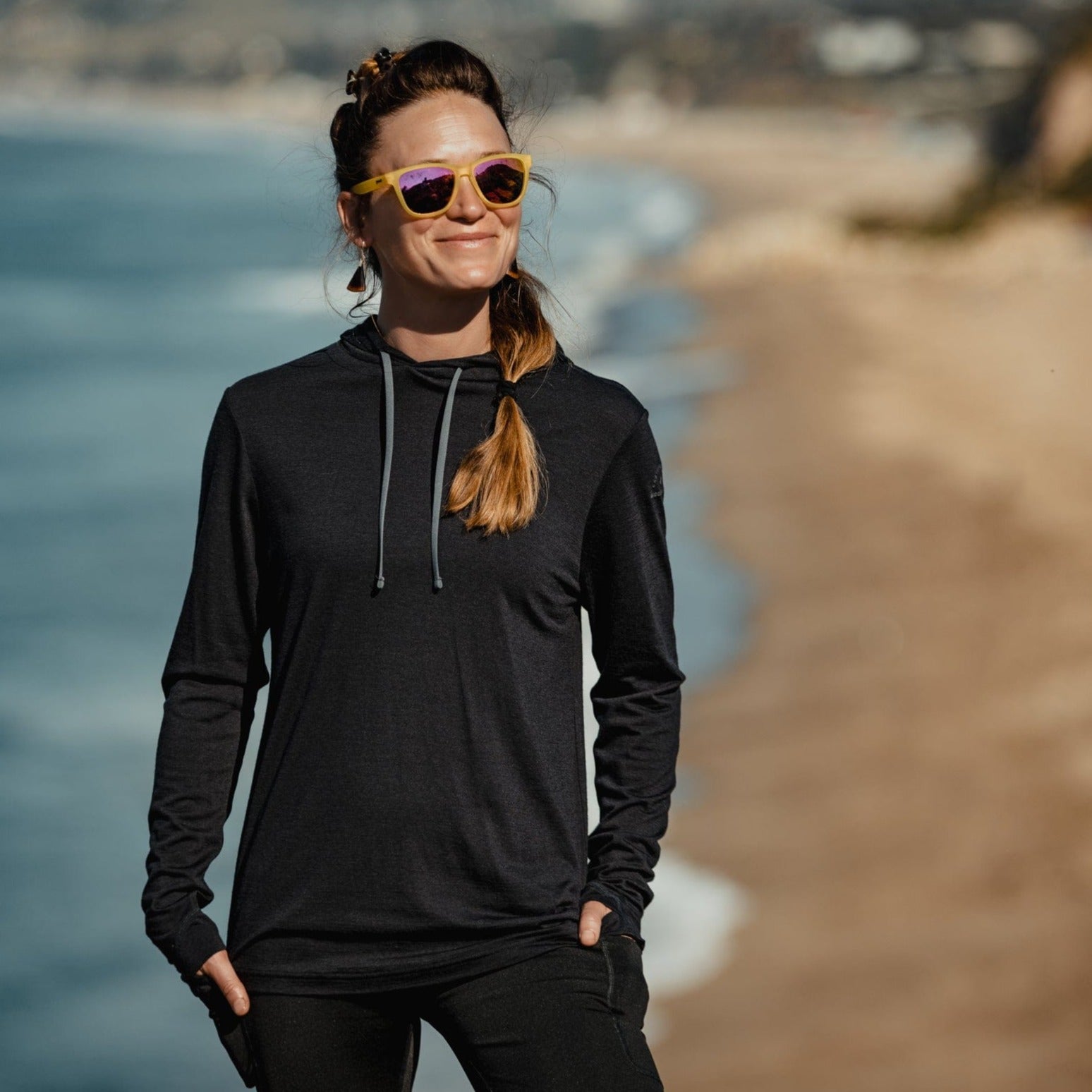 a woman wearing a black Solstice Merino Sun Hoodie