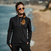 a woman wearing a black Solstice Merino Sun Hoodie