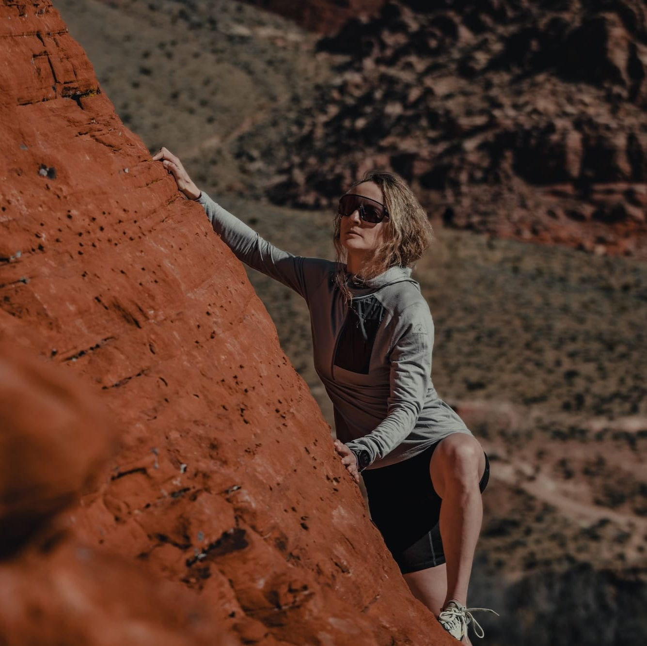 a woman bouldering wearing a Sierra Cement Solstice Pro Sun Hoodie