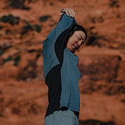 a man stretching in a Pursuit Pro Ultralight Merino Hoodie