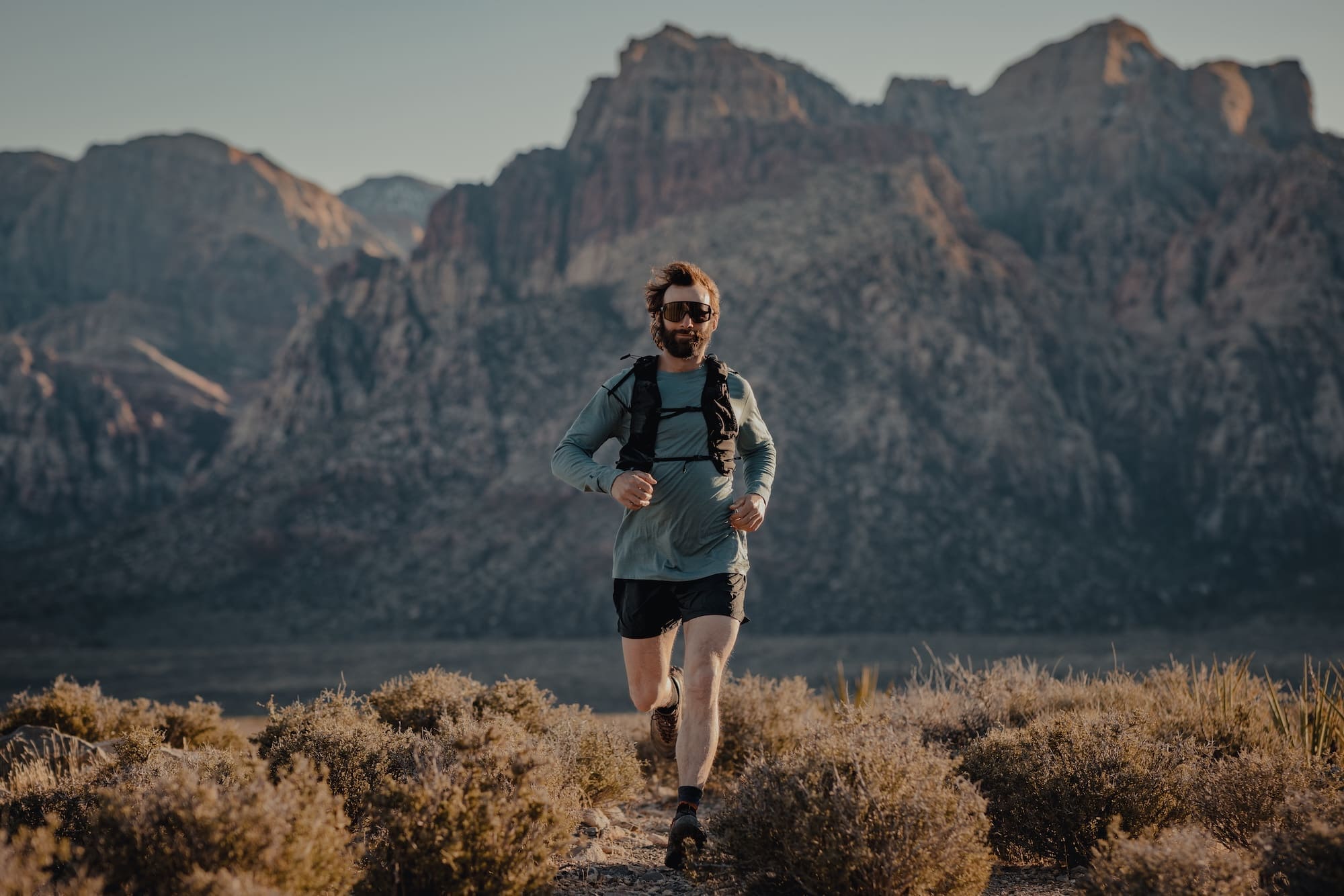a man wearing a long sleeve Pursuit shirt running through the desert