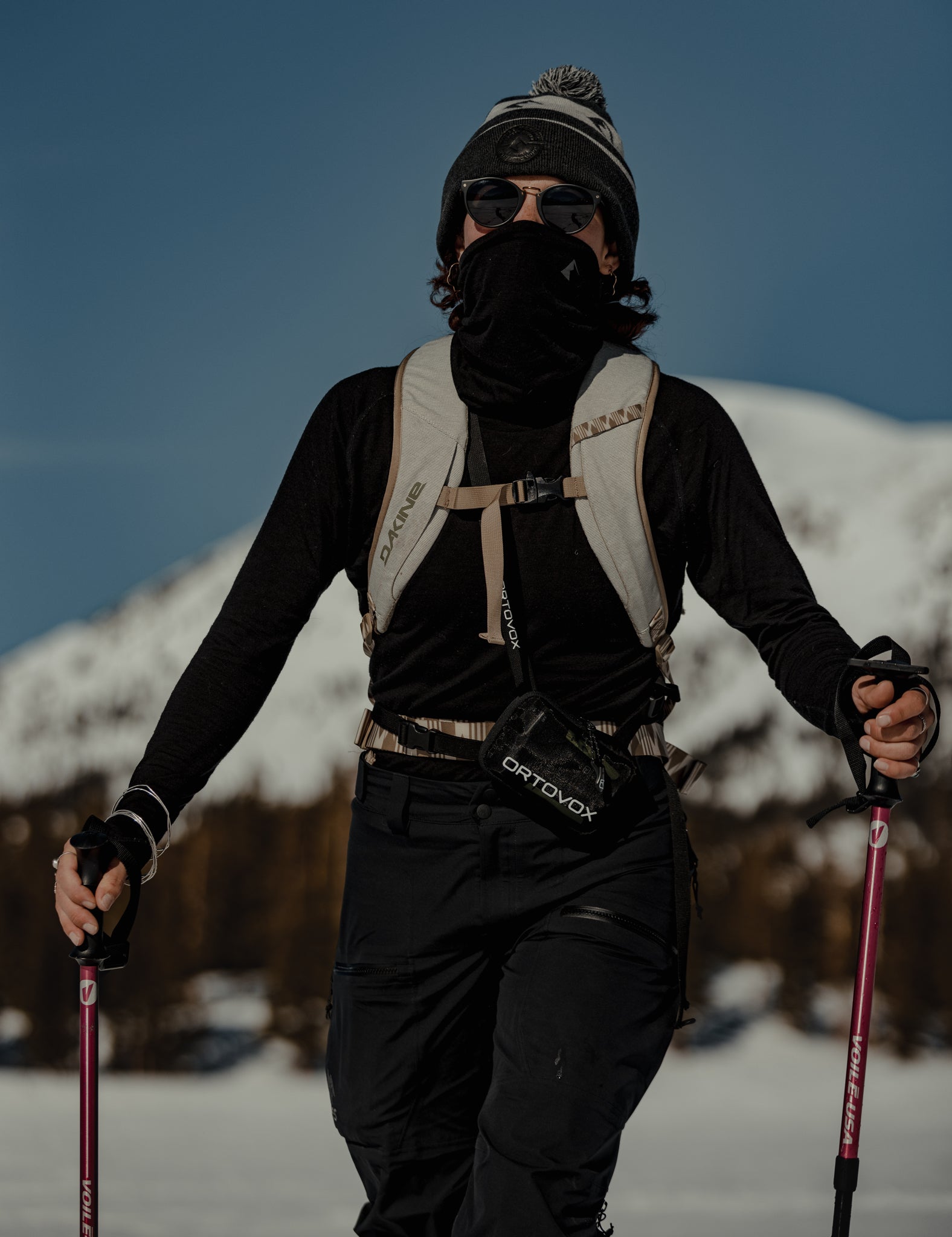 a woman wears Ridge Merino sun protection layers on a sunny bluebird ski touring day