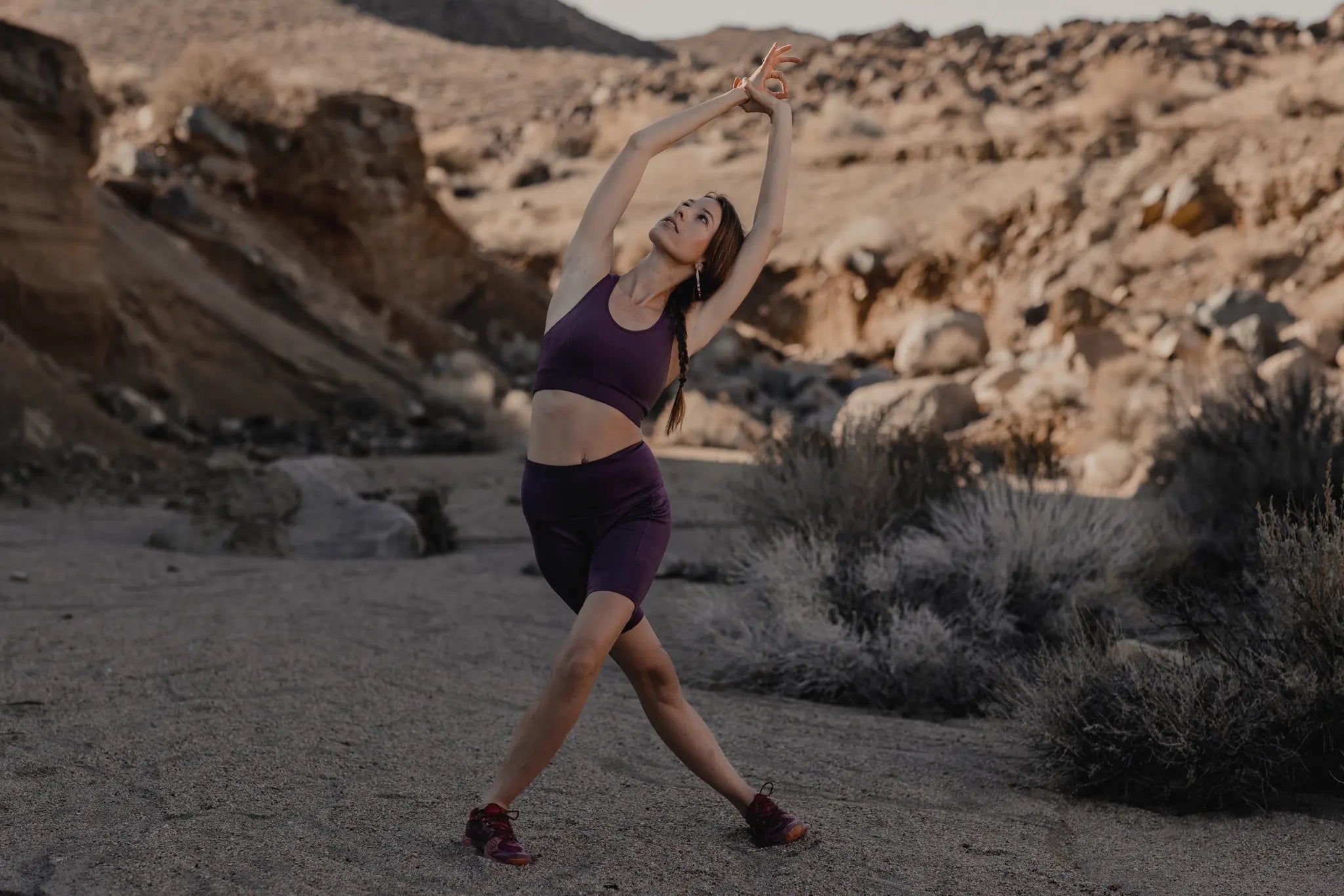 a woman does a yoga pose in the desert wearing matching Ridge Merino shorts and sports bra