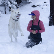 a girl wearing a Ridge Kids' Hyde Merino Hoodie playing with her dog
