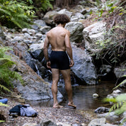 a man wearing Ridge Merino Wool Boxer Briefs dips his toes into a stream on a hike