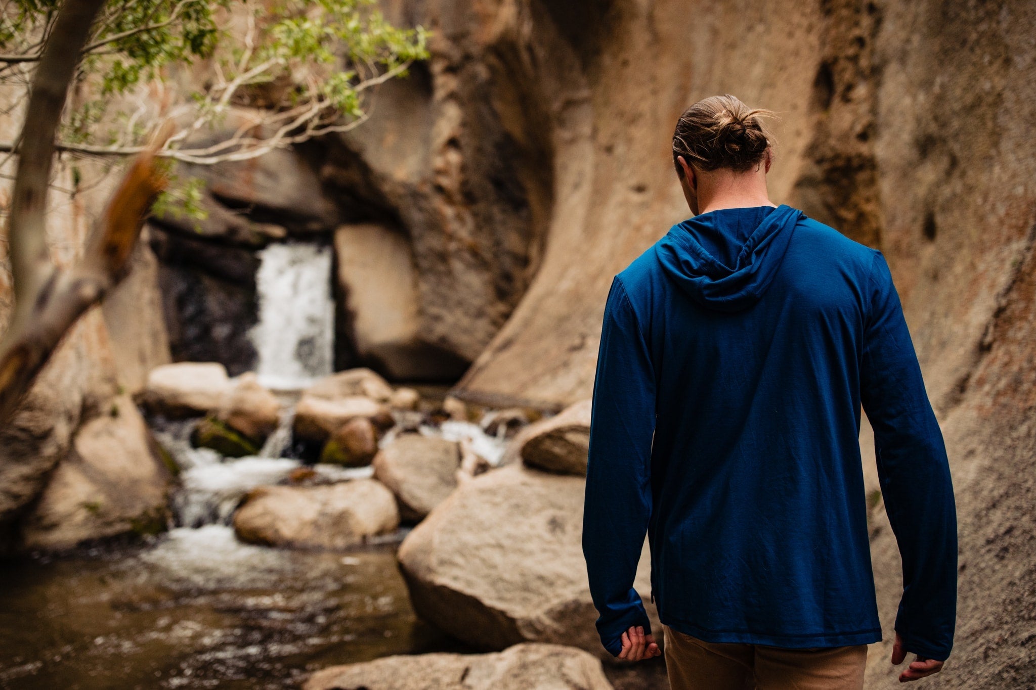 a hiker walking to a waterfall wearing a Ridge Merino Solstice Sun Hoodie for sun protection