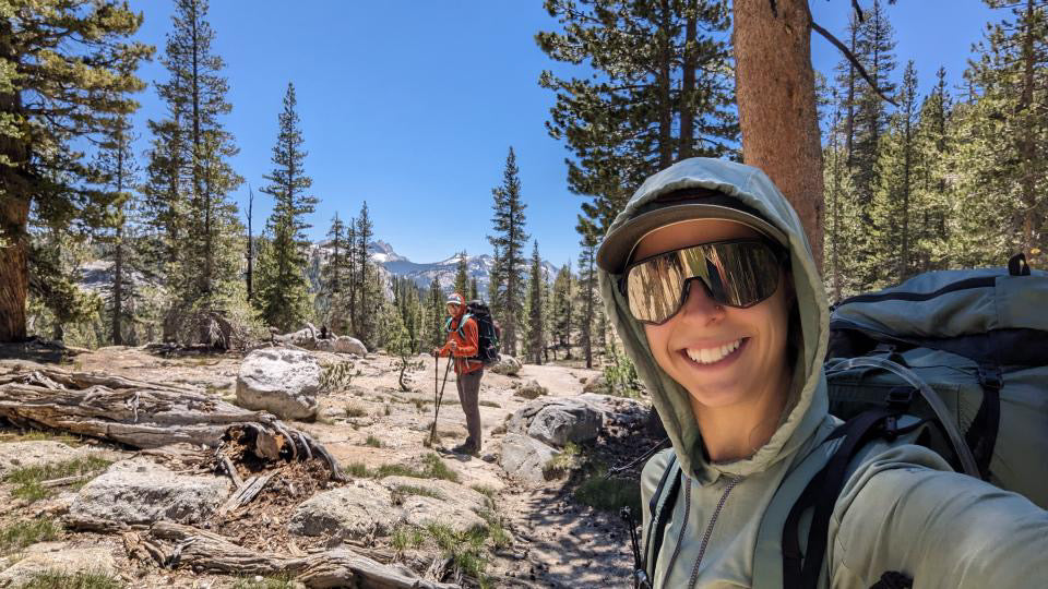 Lauren MacLeod smiles taking a selfie with her hiking partner wearing a Solstice Sun Hoodie