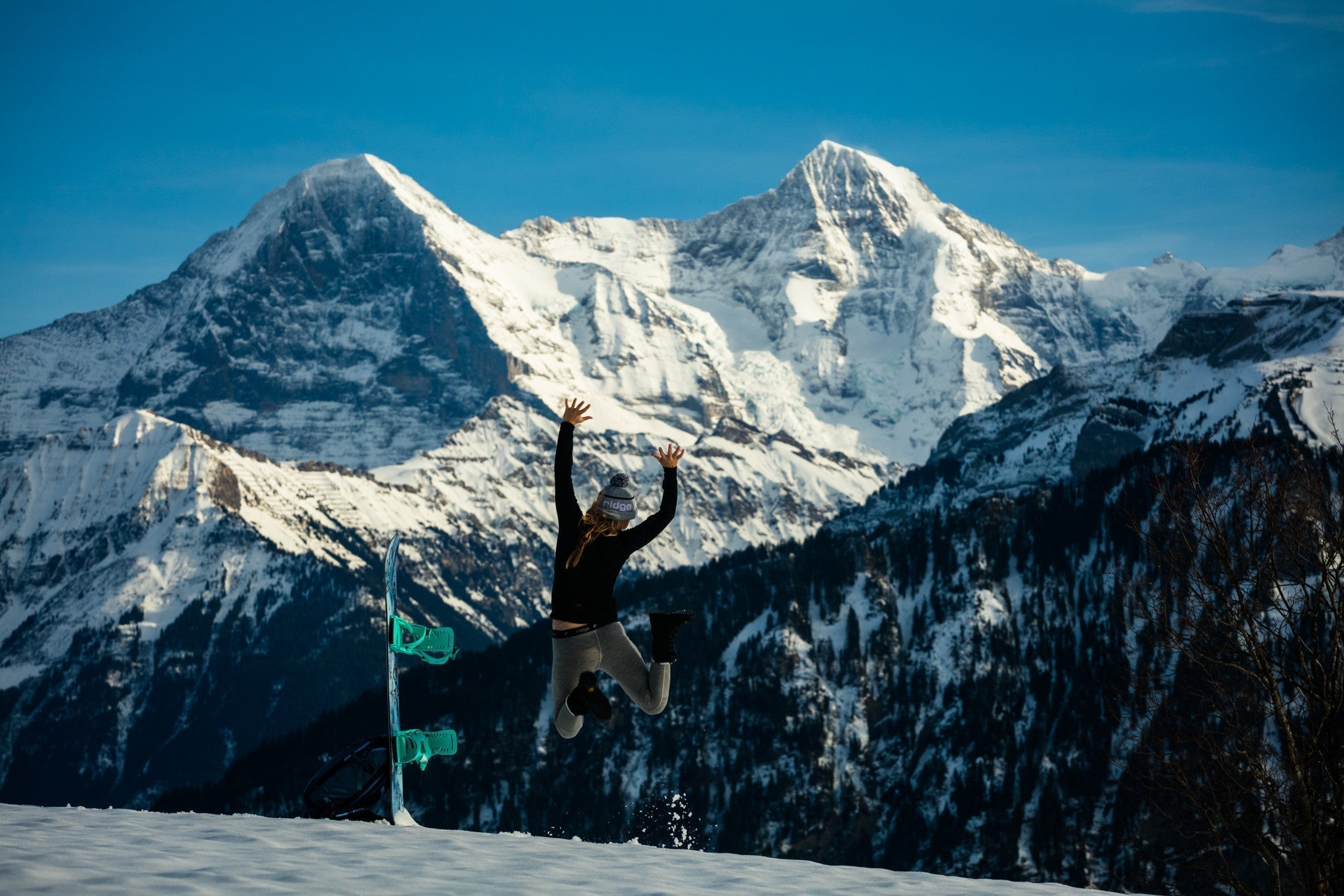 Alison Teal jumping for joy in front of a big snowy mountains
