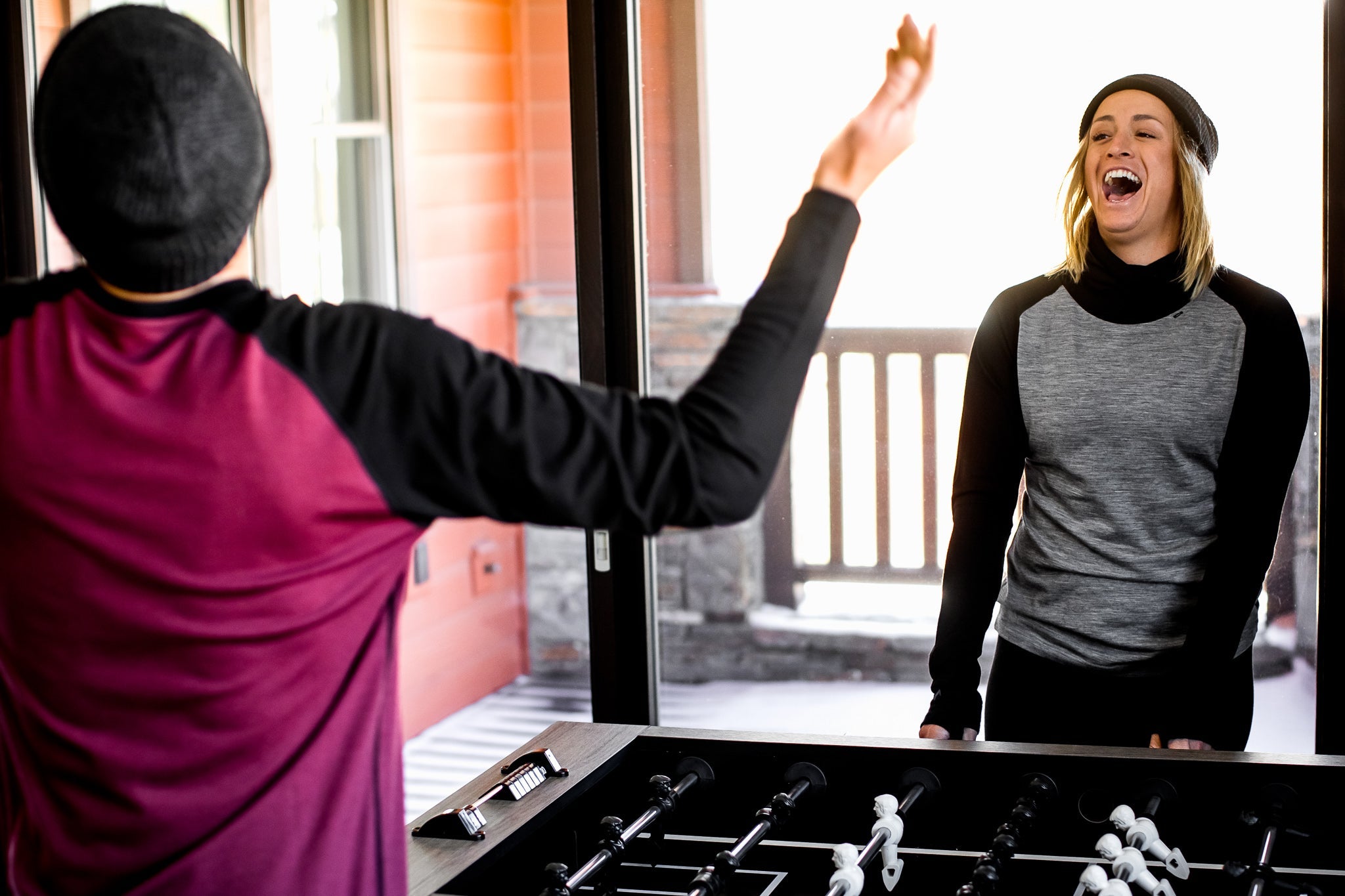 two friends laugh playing foosball together wearing Ridge Merino base layers