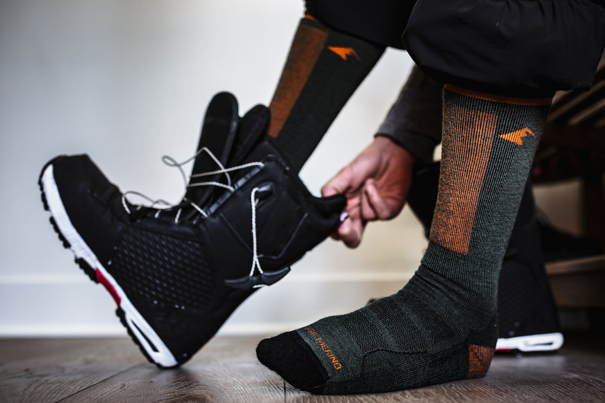 a snowboarder putting on snowboard boots over Ridge Merino ski socks