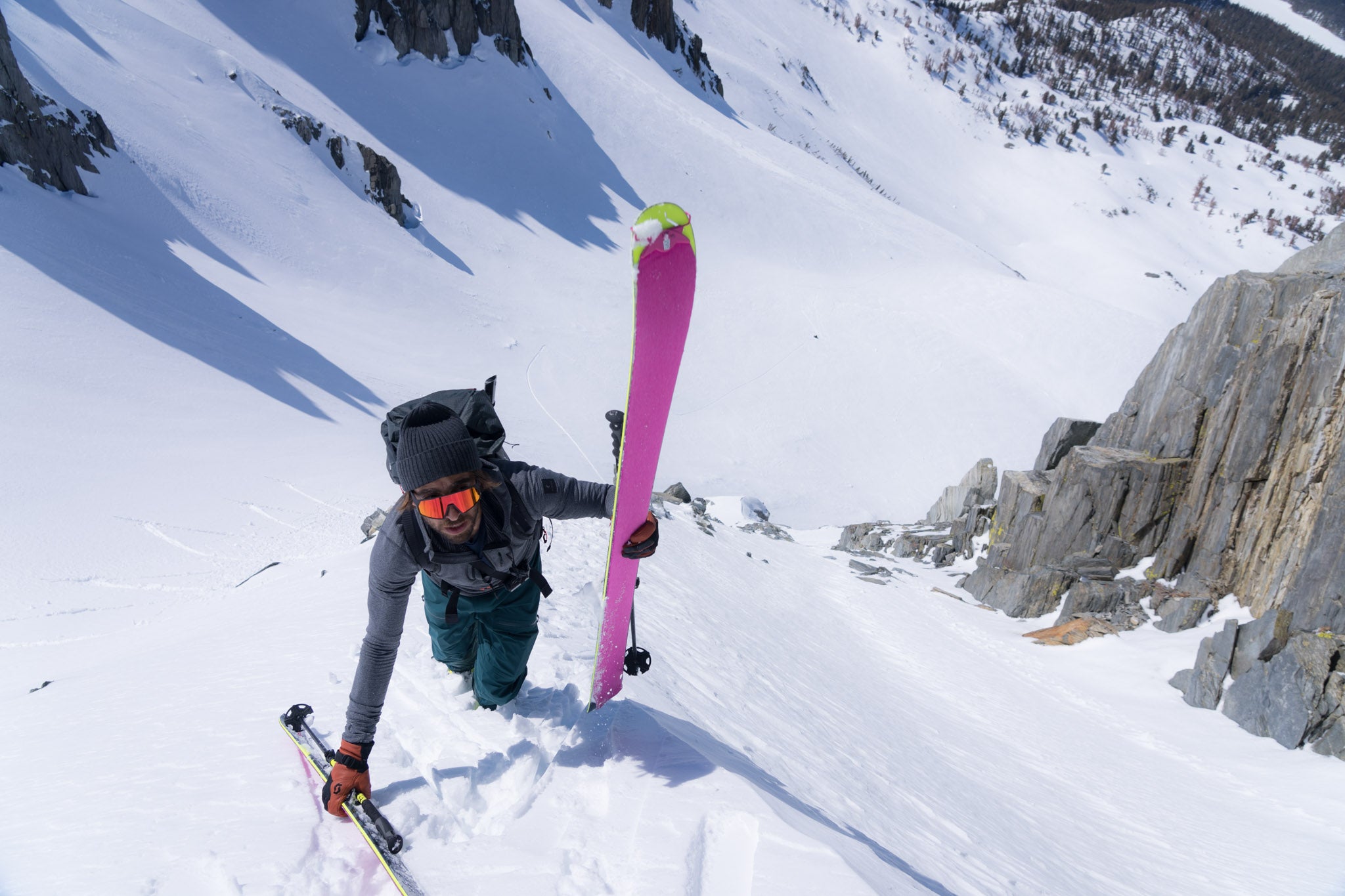 Sam Cohen boot packs up a steep couloir wearing the Ridge Convict Canyon hoodie