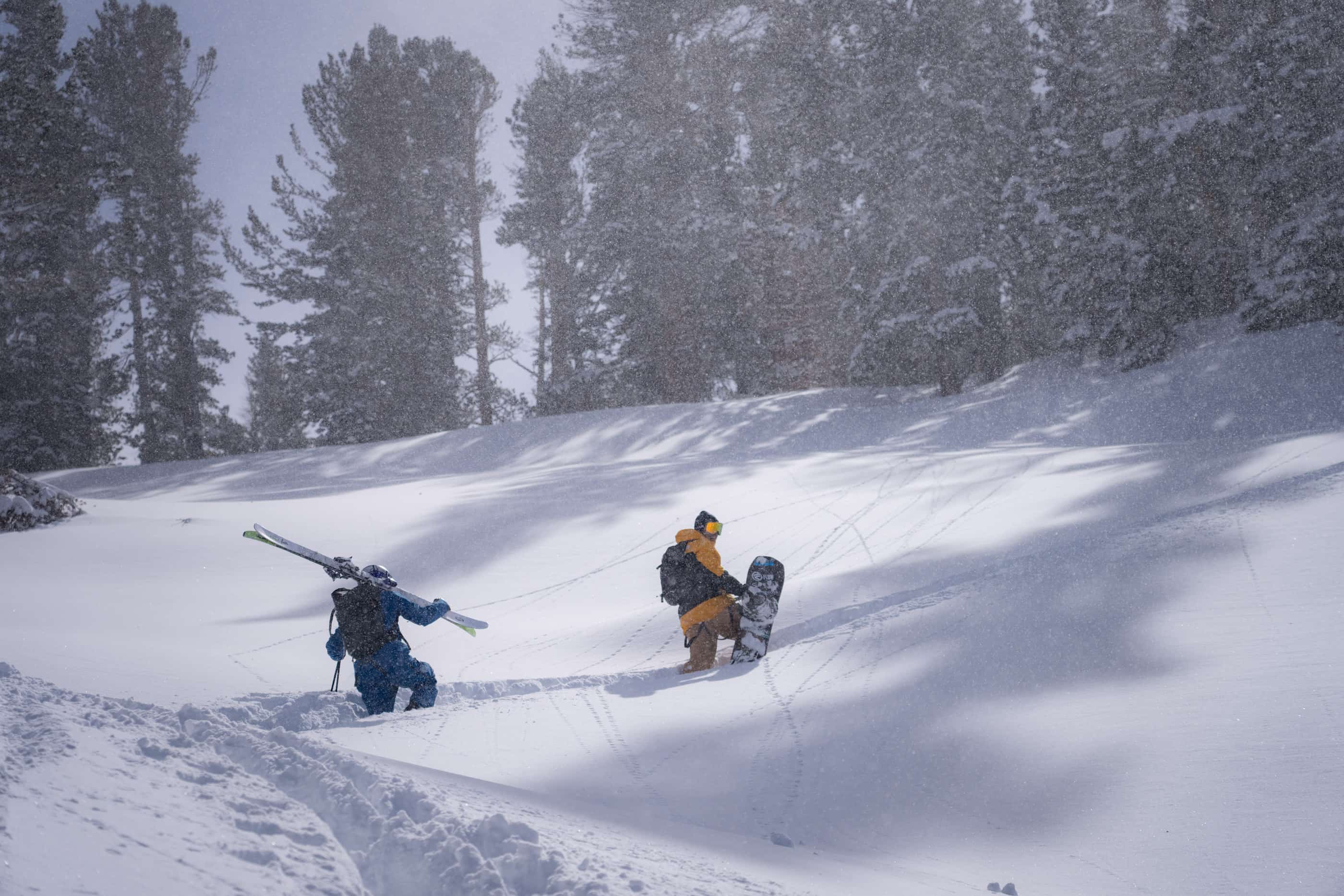a skier and a snowboarder hike through deep snow while backcountry skiing in Virginia Lakes, CA