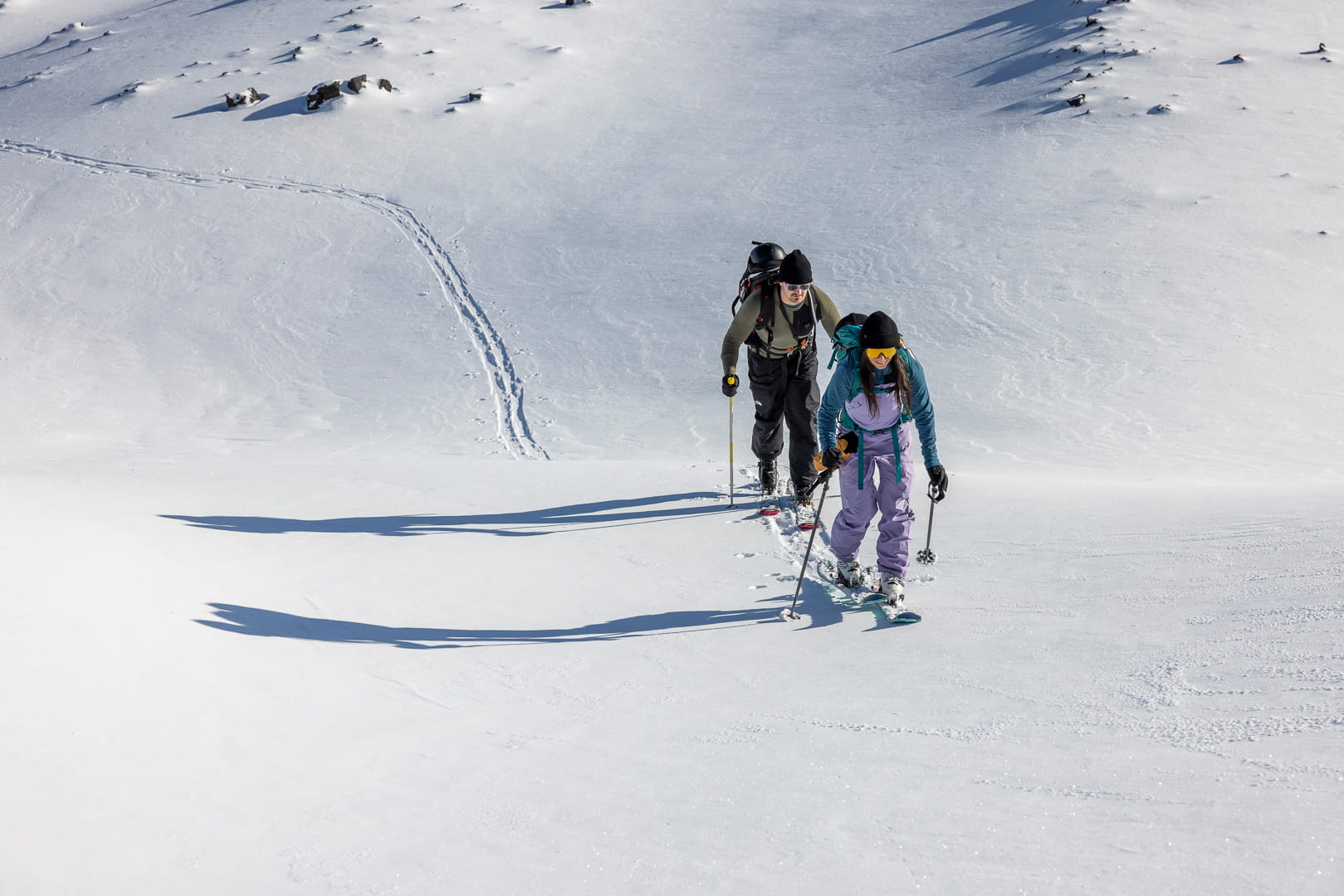 two skiers ascend a hill wearing Ridge Merino base layers and mid layers