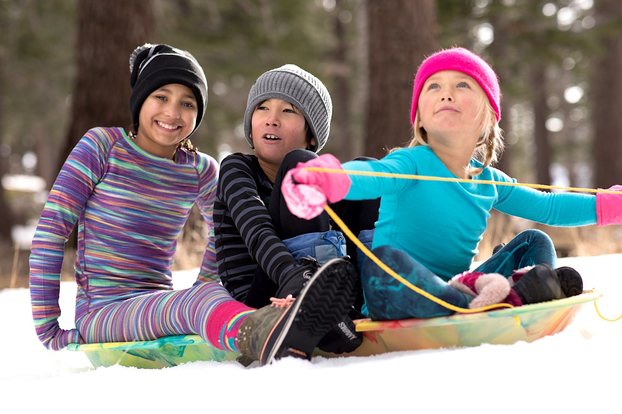 three kids sledding together in Ridge base layers