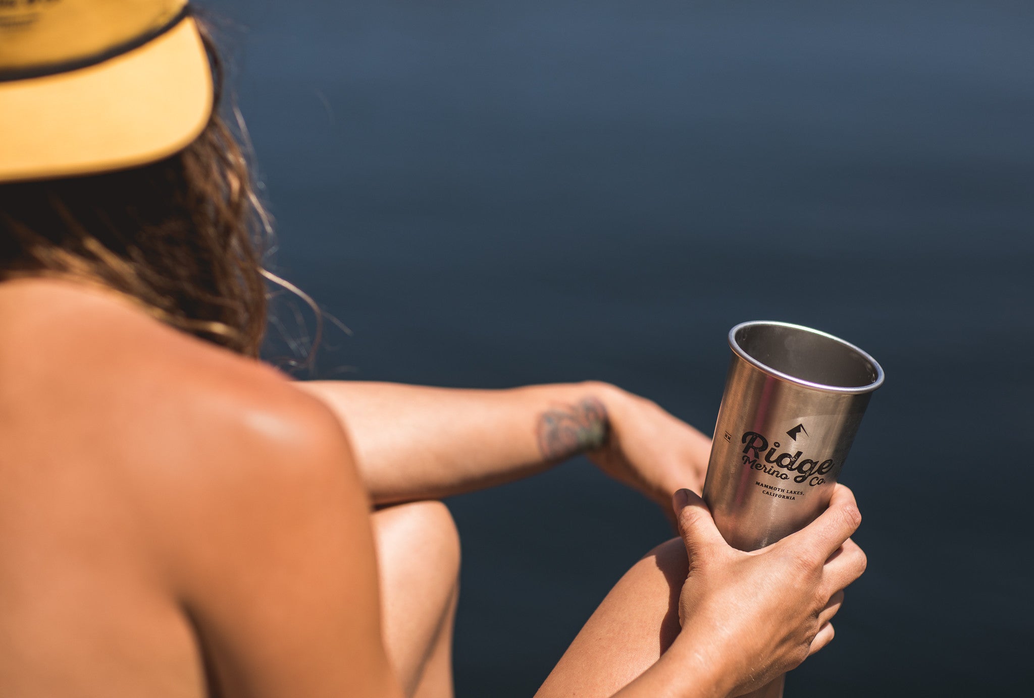 a woman hanging by a backcountry lake holding a Ridge x Klean Kanteen pint cup