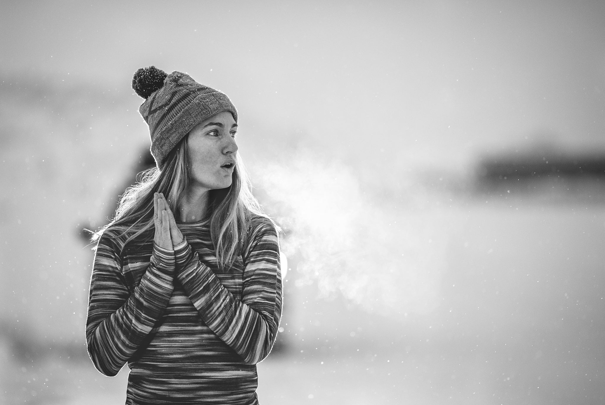 a black and white photo of a woman breathing in the cold wearing striped Ridge base layers