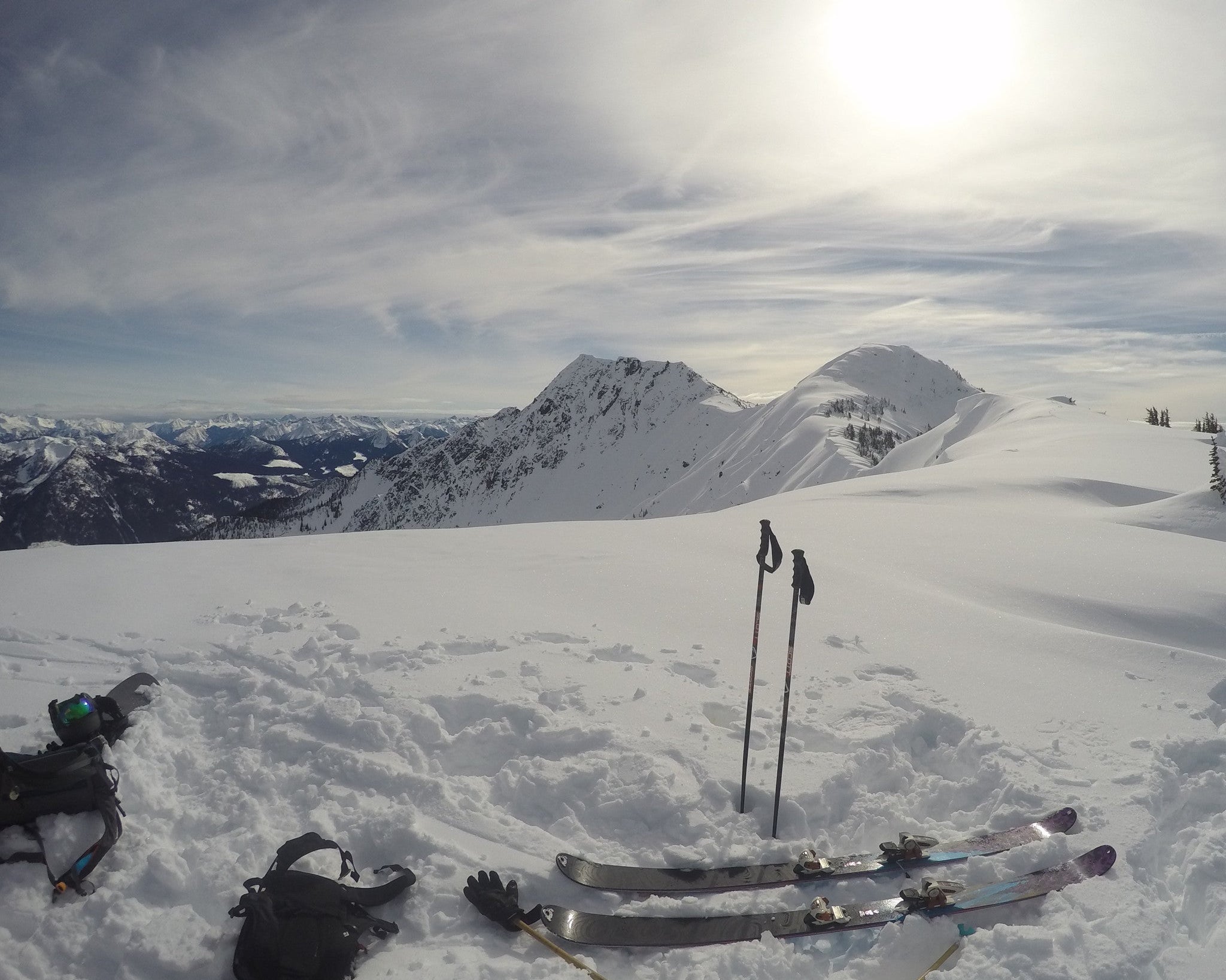 backcountry ski gear laid out at the top of a run on a snowy day