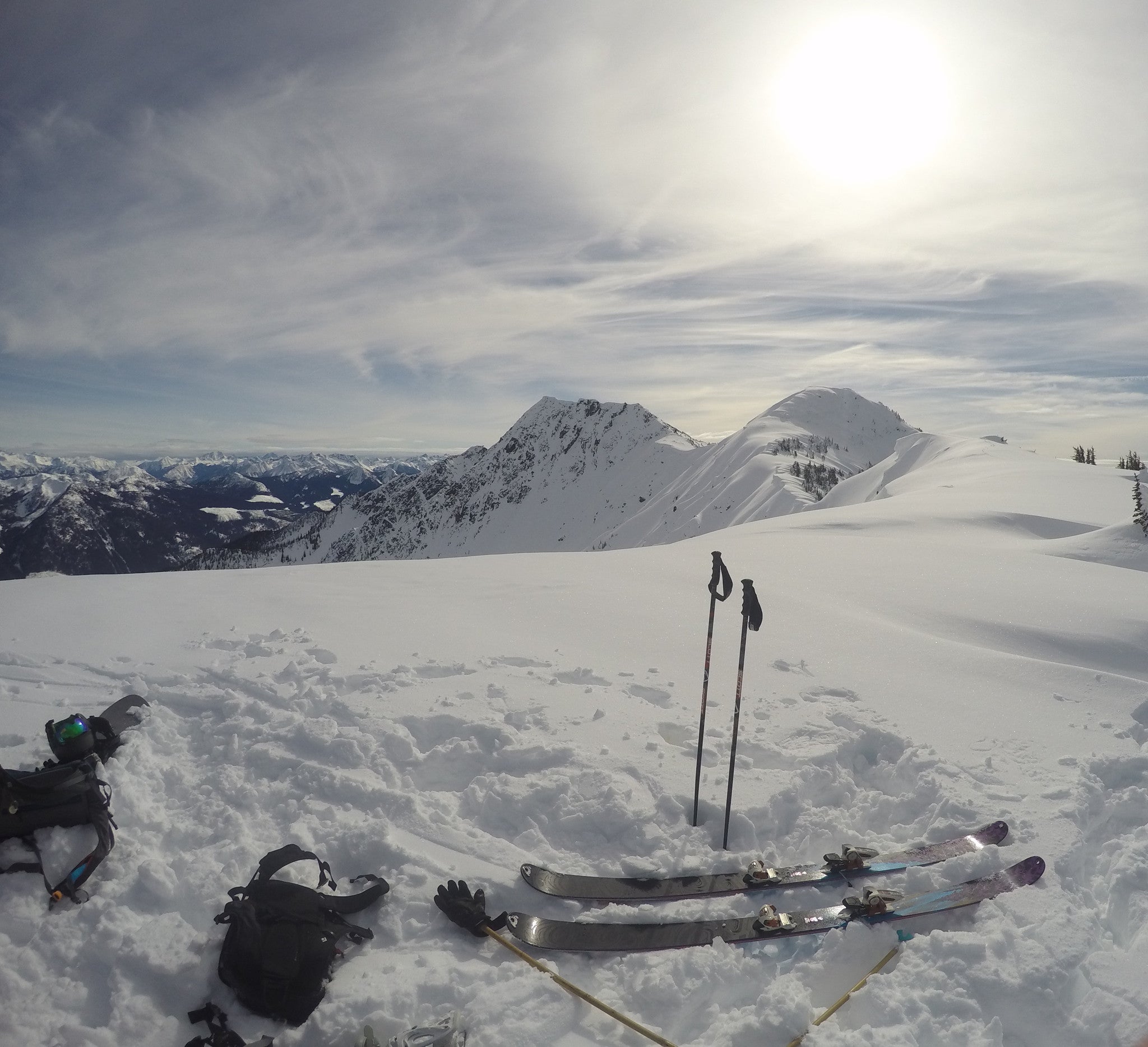 backcountry ski gear laid out at the top of a run on a snowy day