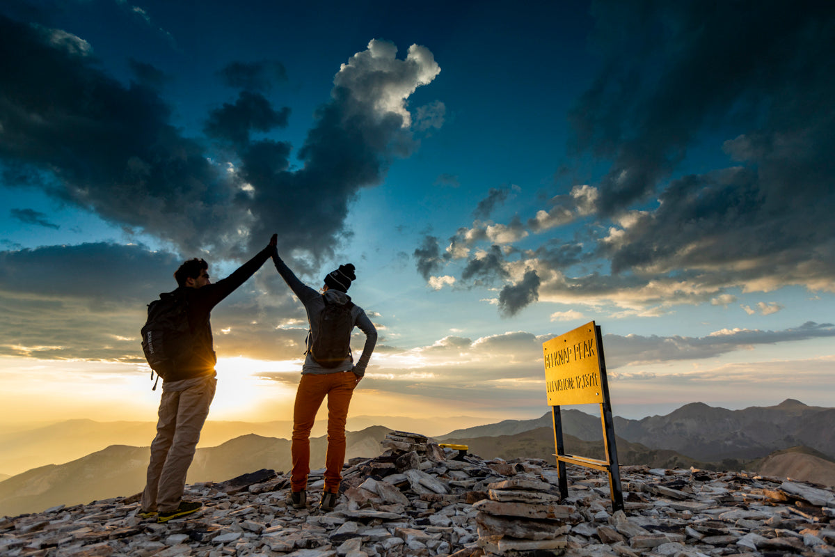 two hikers high fiving at the summit