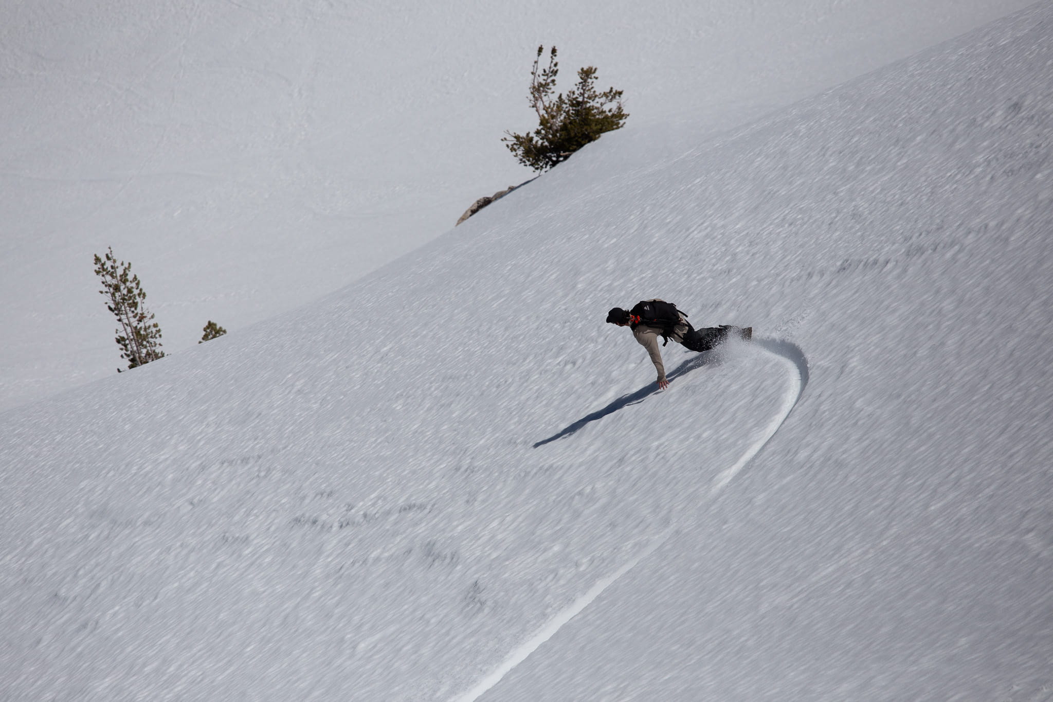 a snowboarder cruises down a spring ski run in the backcountry in Mammoth Lakes, CA