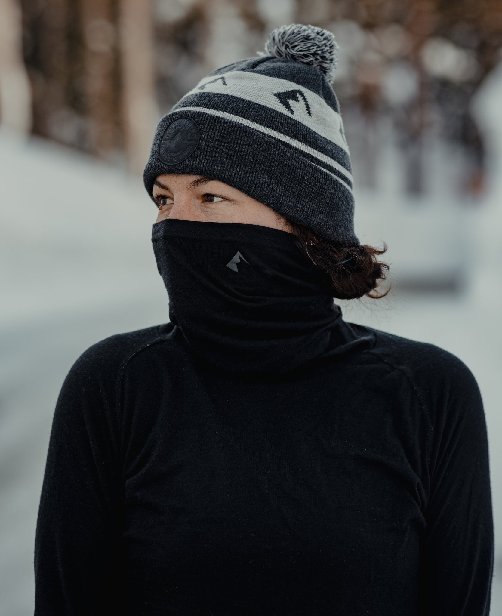 a woman wearing the Aspect Merino Wool High Neck Top and Ridge Logo Pom Merino Wool Beanie