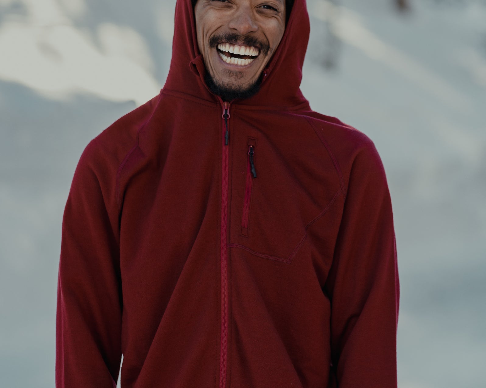 a man smiles big wearing a Ridge Merino jacket