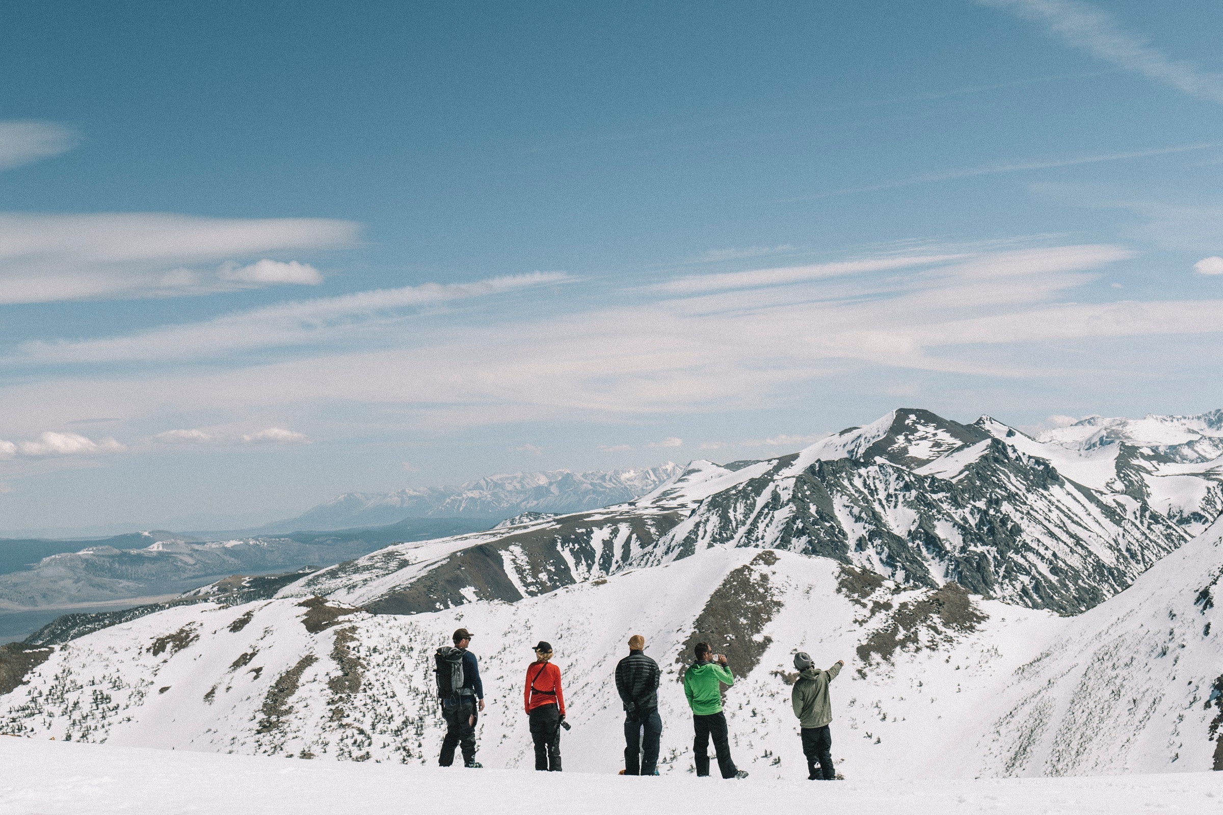 a group of backcountry skiers overlooking snowy peaks on a sunny day