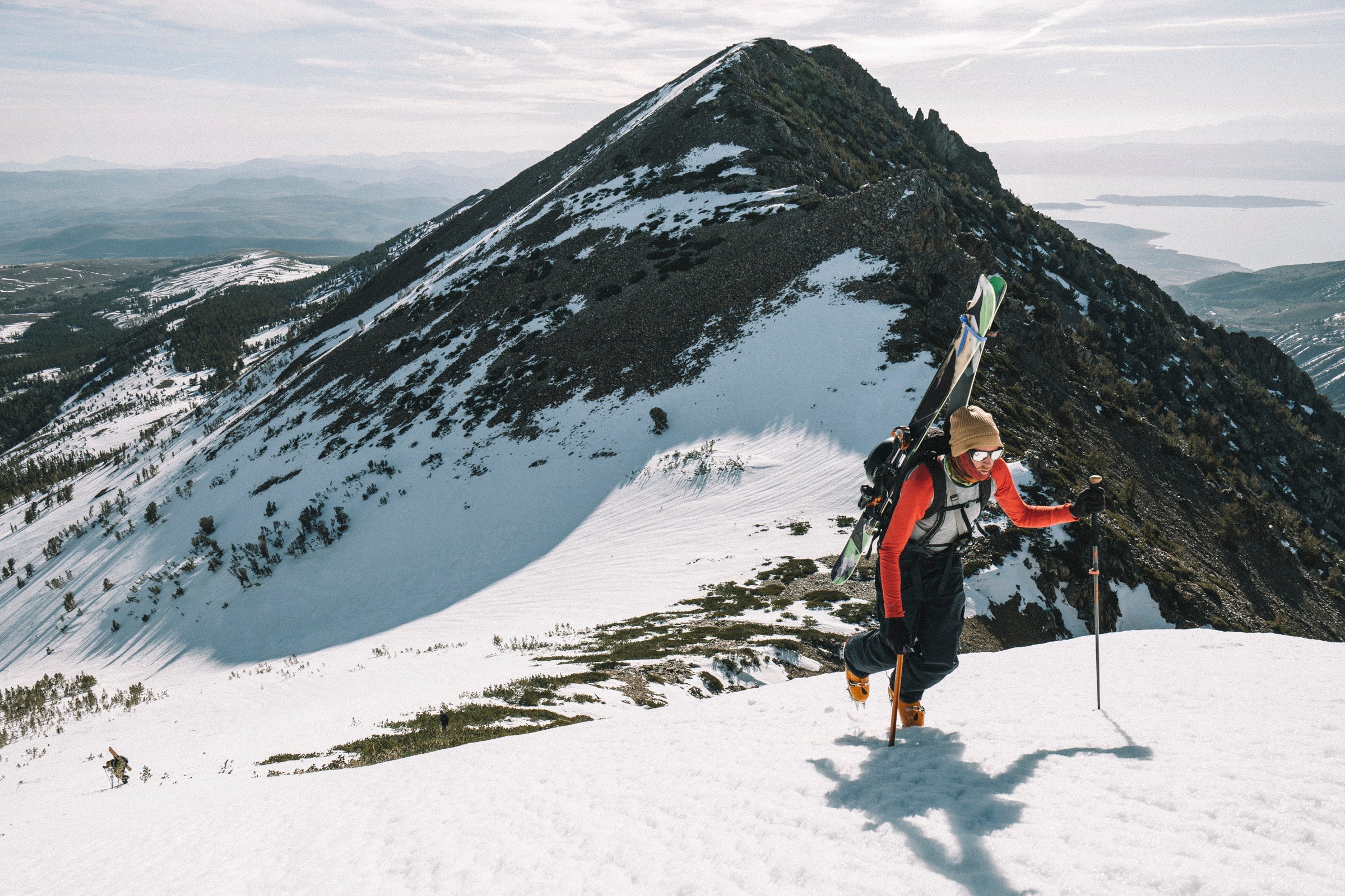 a backcountry skier walking up a snowy mountain in red Ridge Merino base layers