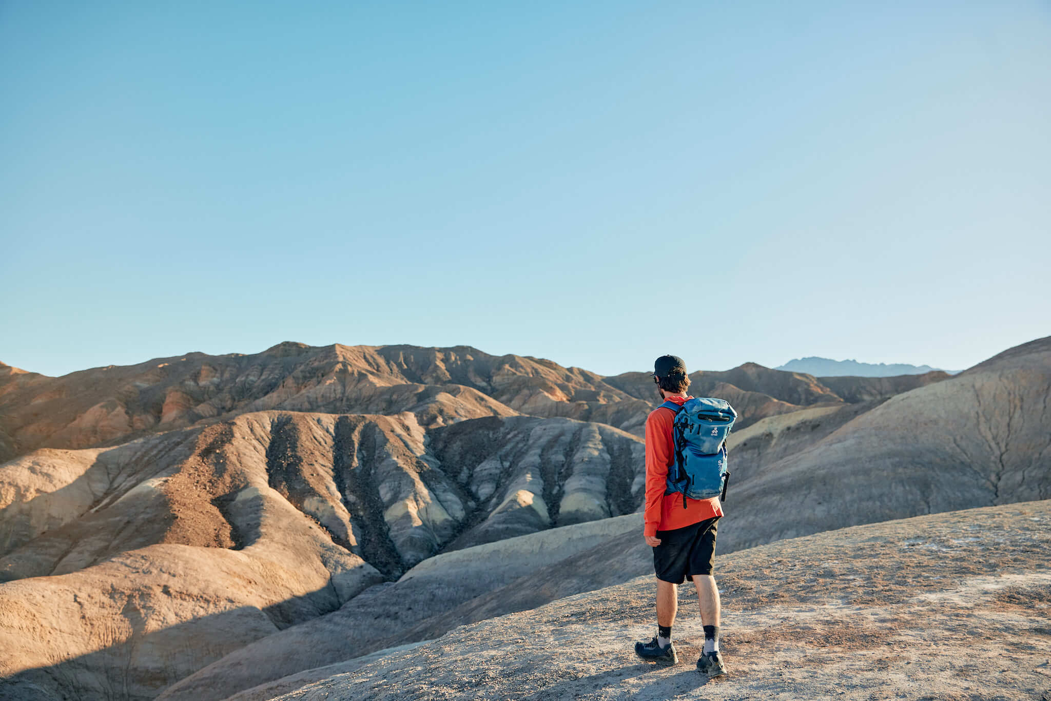 a man on a hike in Death Valley wearing a Ridge Merino Solstice Sun Hoodie, a great clothing piece for traveling