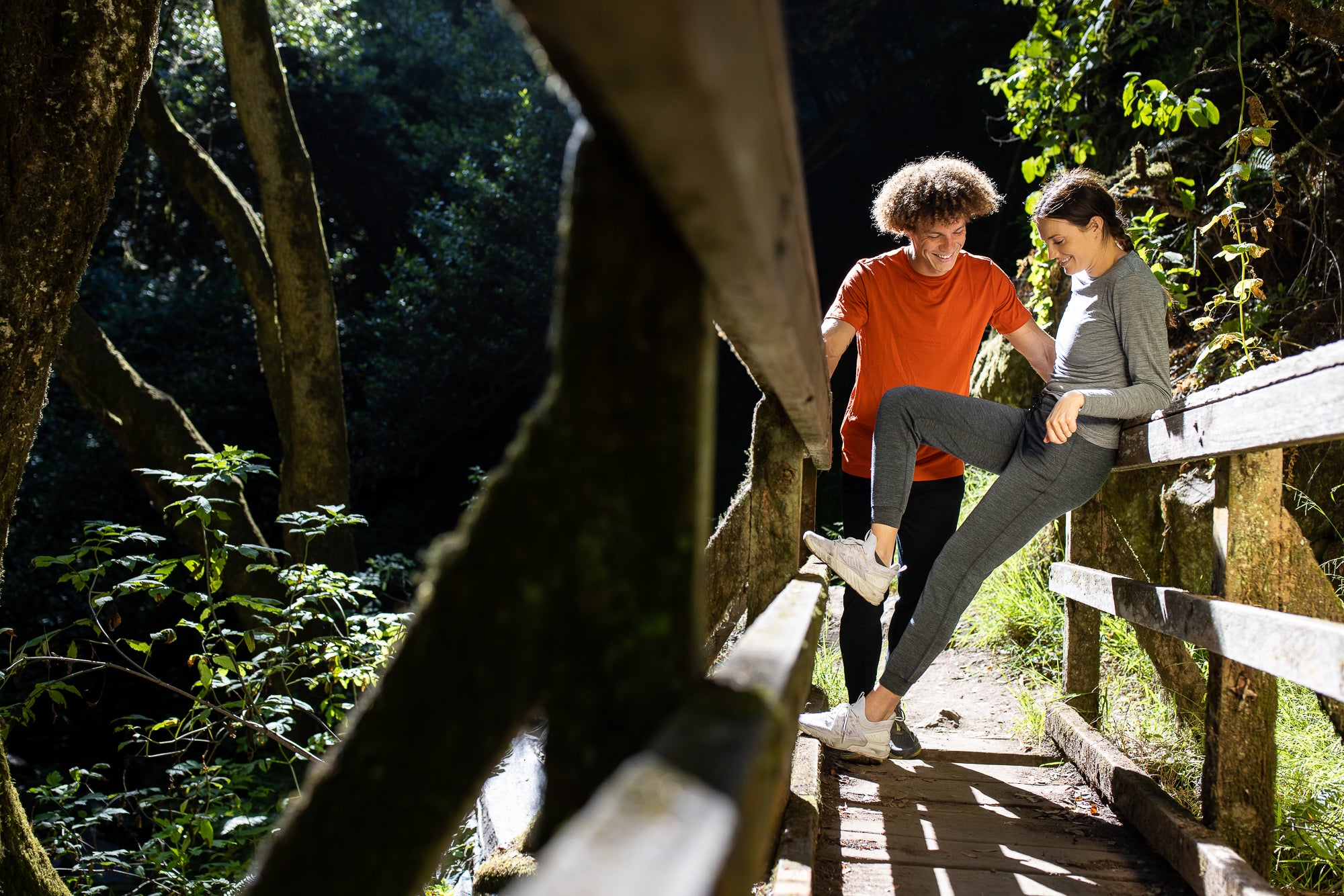 a man and a woman stand on a bridge wearing Ridge Merino clothing