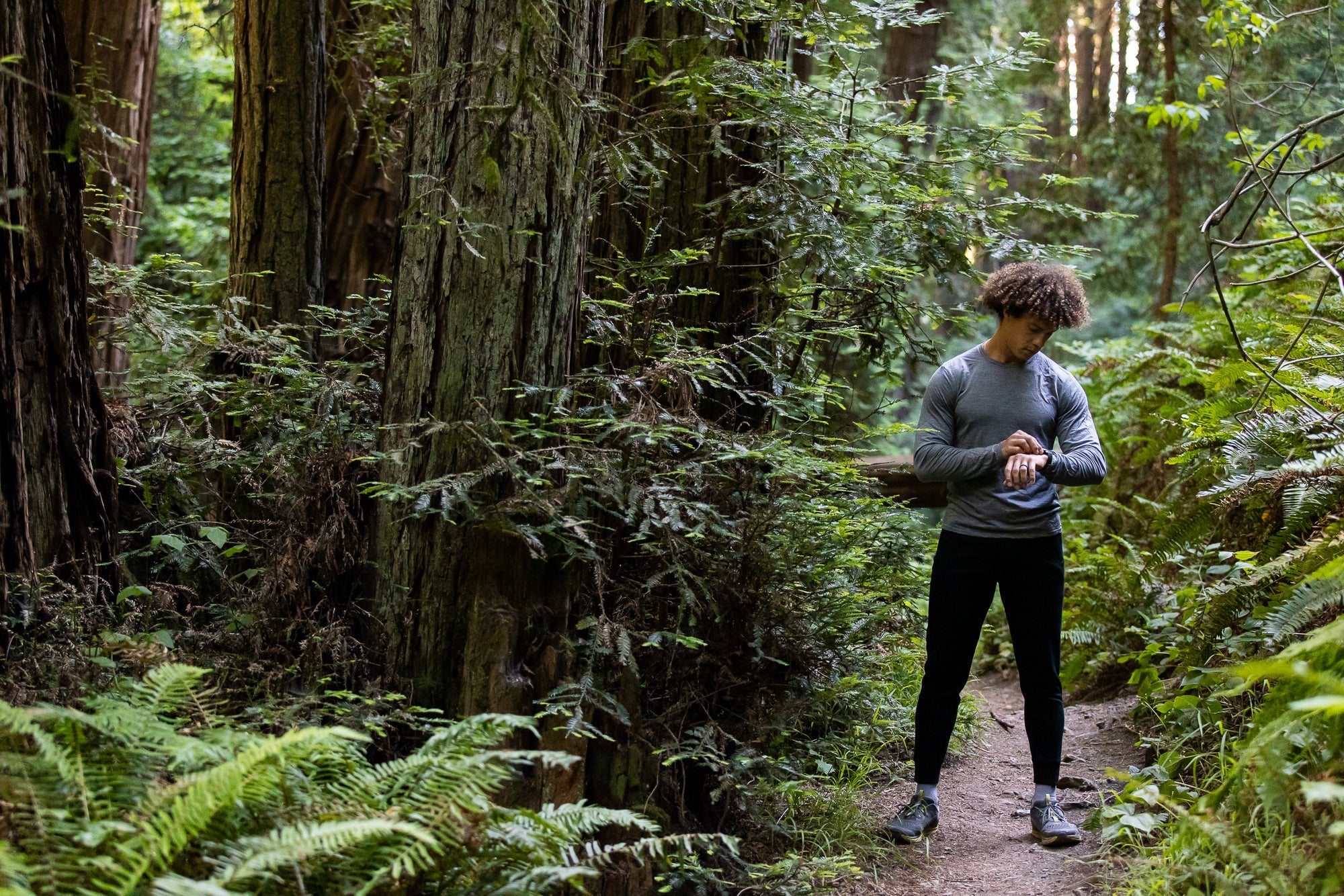 a man checks his watch on a forest run