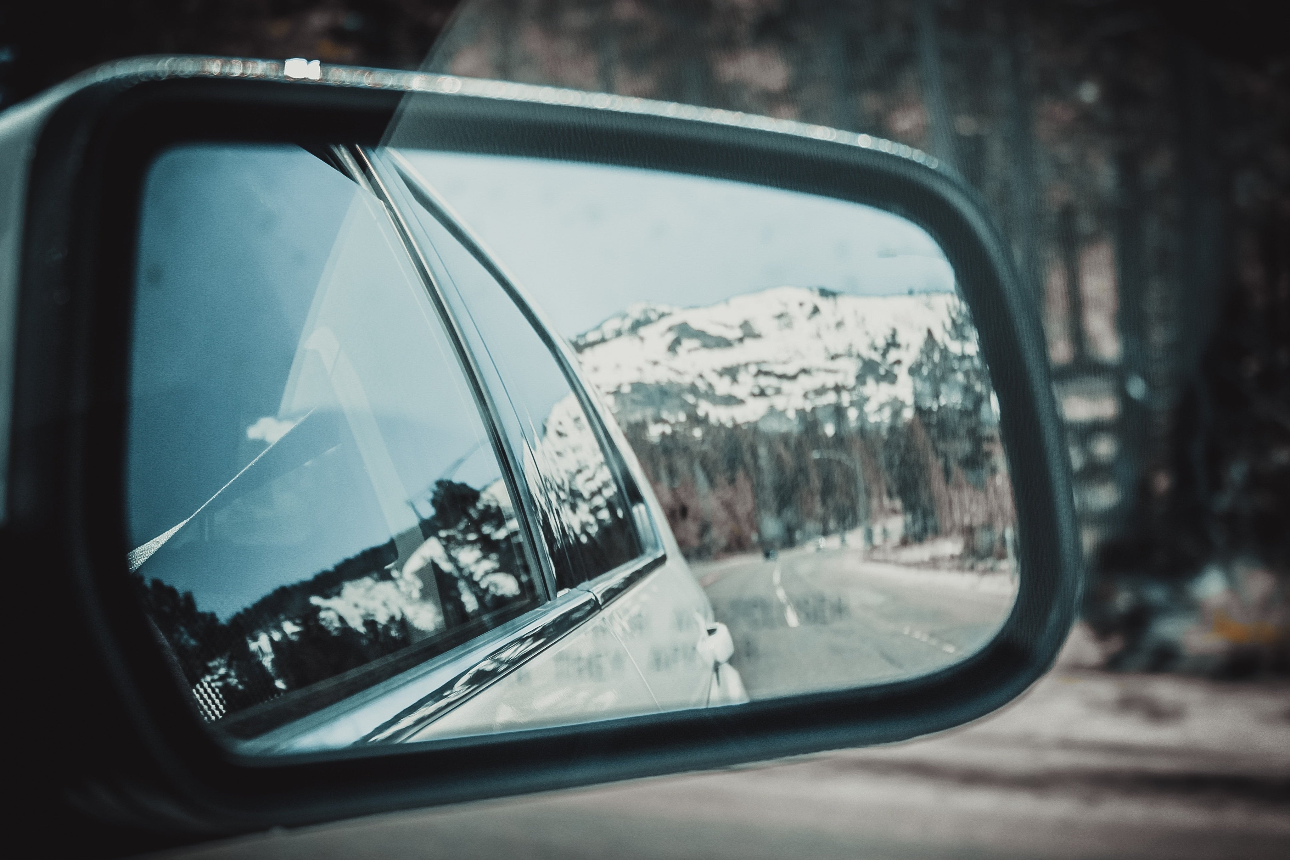 snowy mountains seen in the rear view mirror of a car