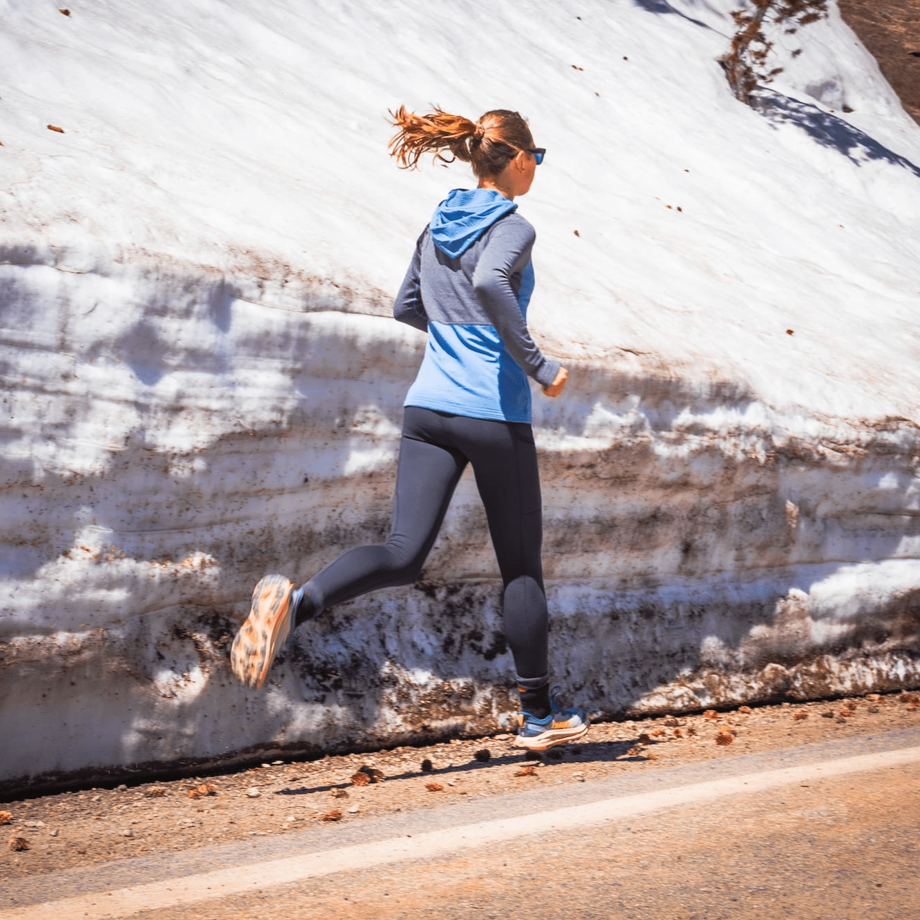 a woman running down a road in Northwind Merino Tights and a Convict Canyon Hoodie