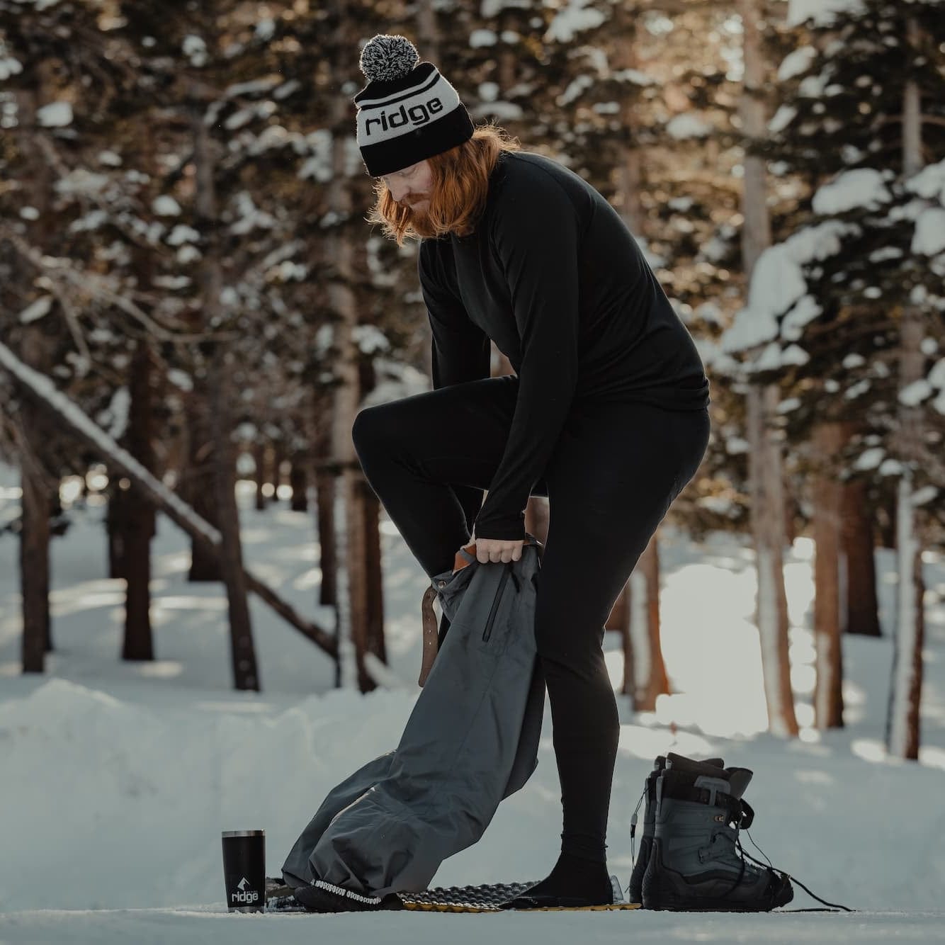 a man putting on ski pants over his base layers