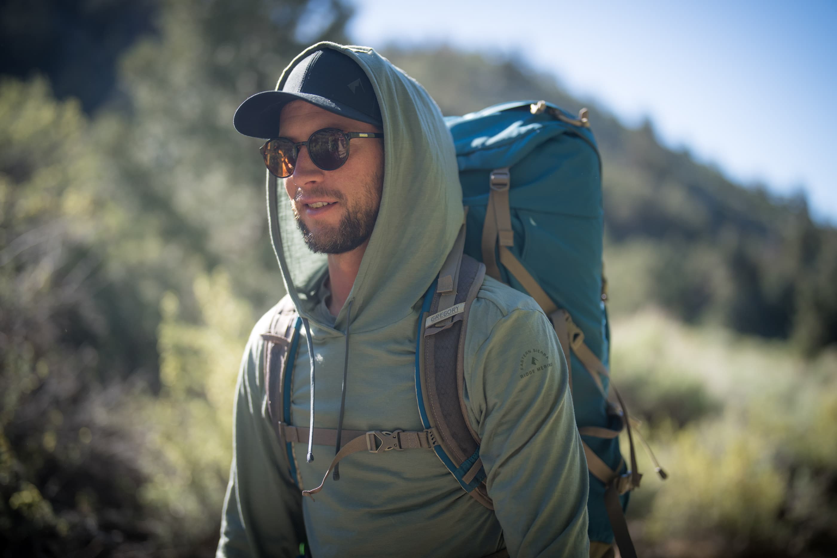 a man backpacking in a green Solstice Sun Hoodie