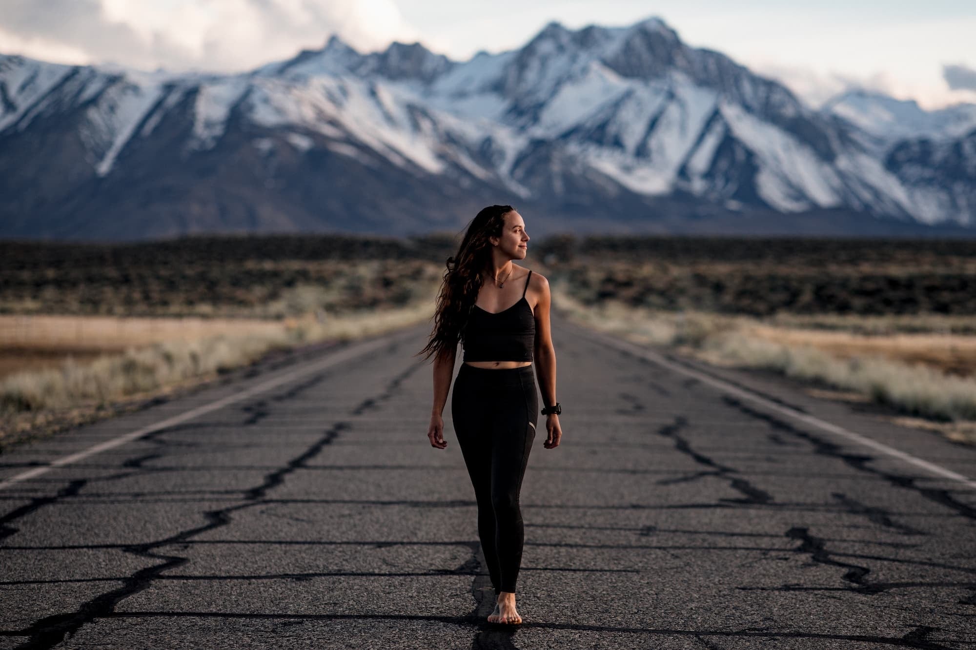 a woman walking on a road in the mountains wearing a Ridge Merino Bralette and Ridge Crowley Compression Running Leggings