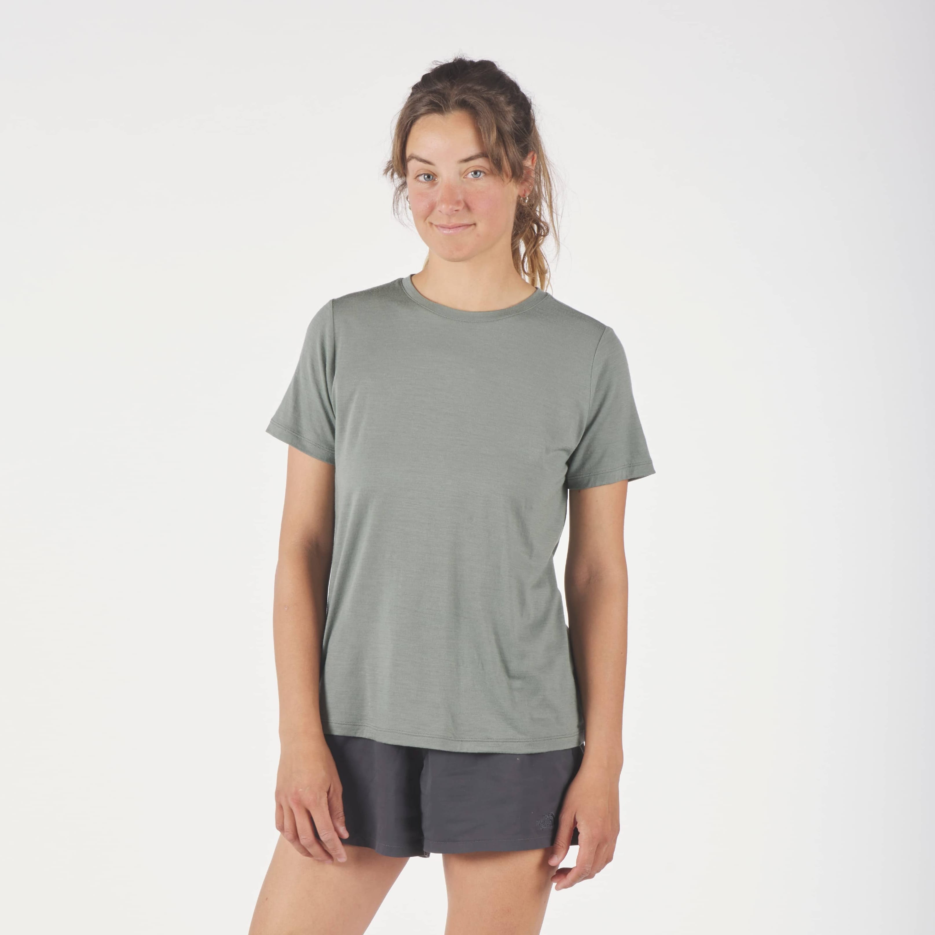a woman wearing a green Journey Merino Wool T-shirt with running shorts