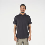 Man wearing a black polo and beige pants on a white background