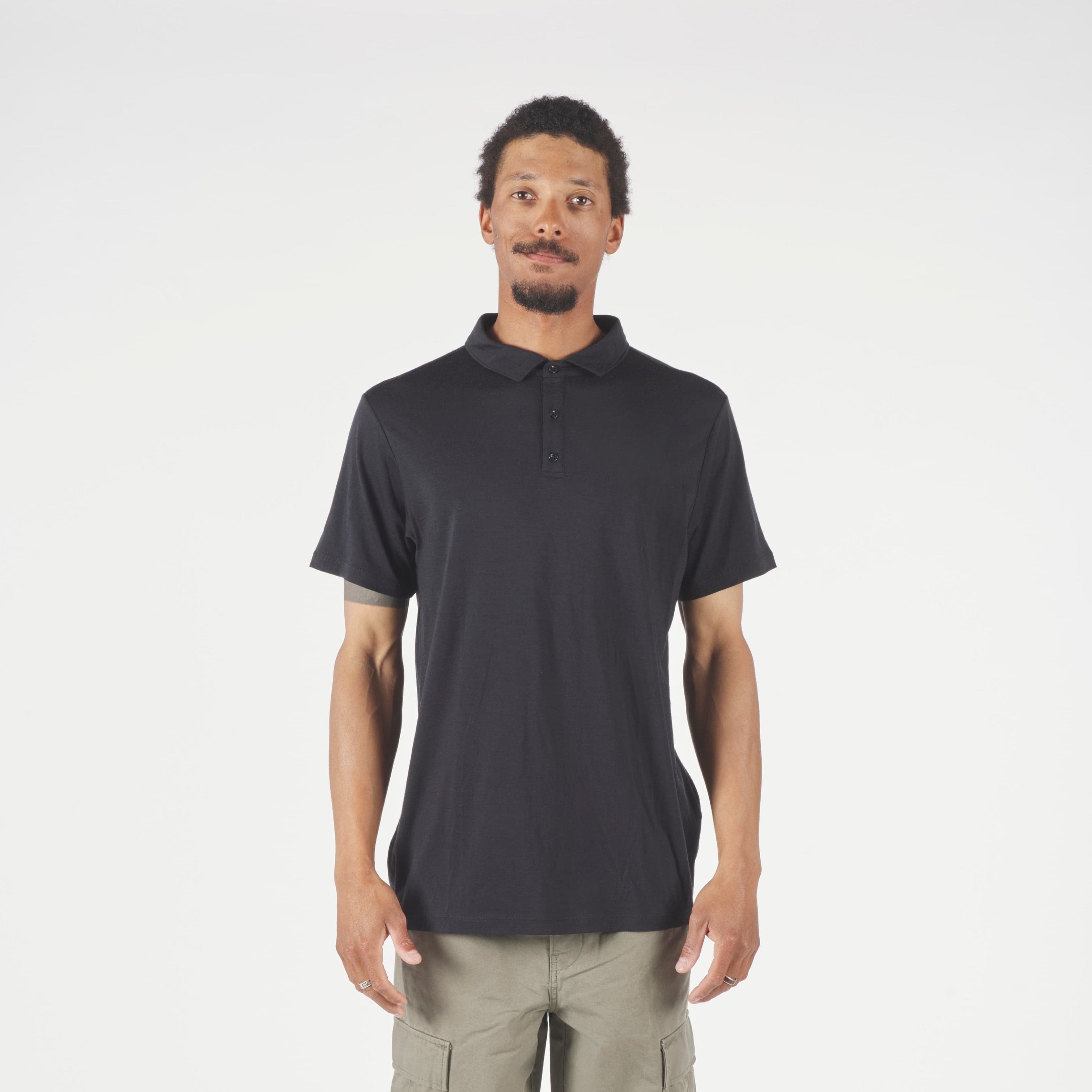 Man wearing a black polo and beige pants on a white background