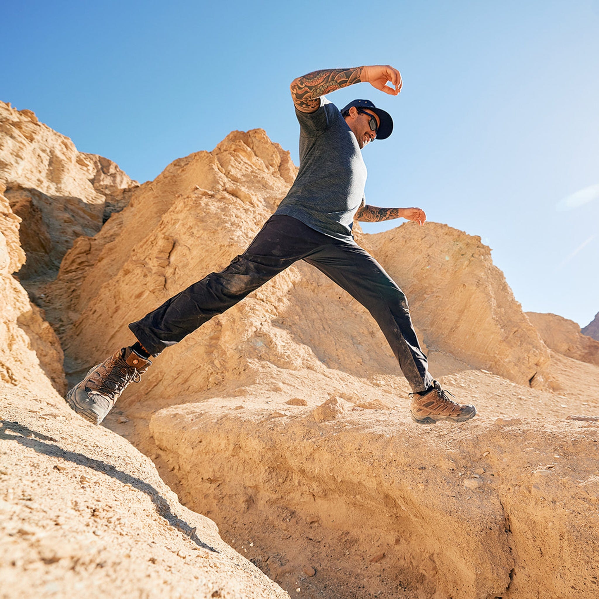 A man jumps from one rock to another in Death Valley wearing the Natural Merino Tencel Tee