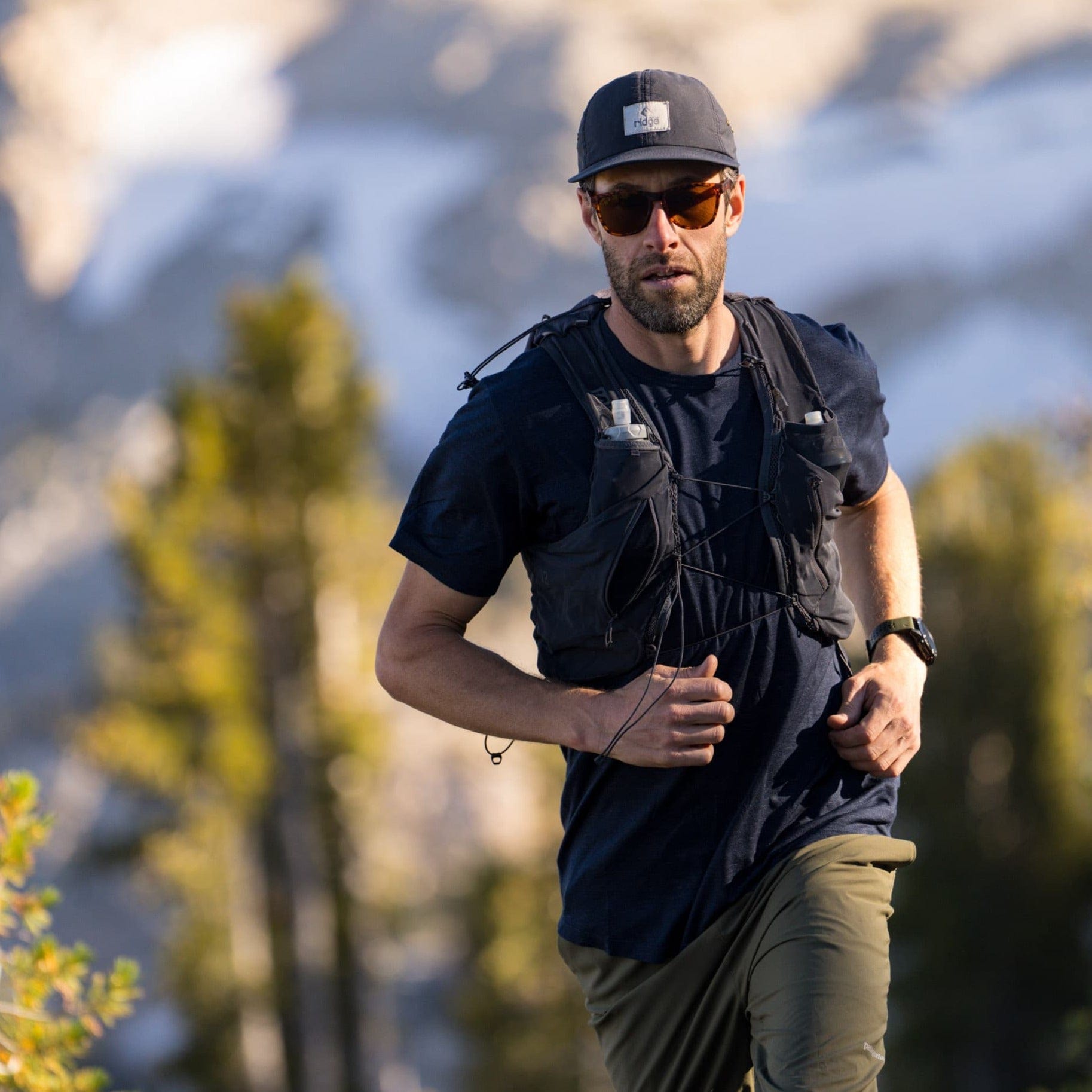 a man goes for a trail run in Mammoth Lakes wearing a Pursuit tee and Ridge Merino hat