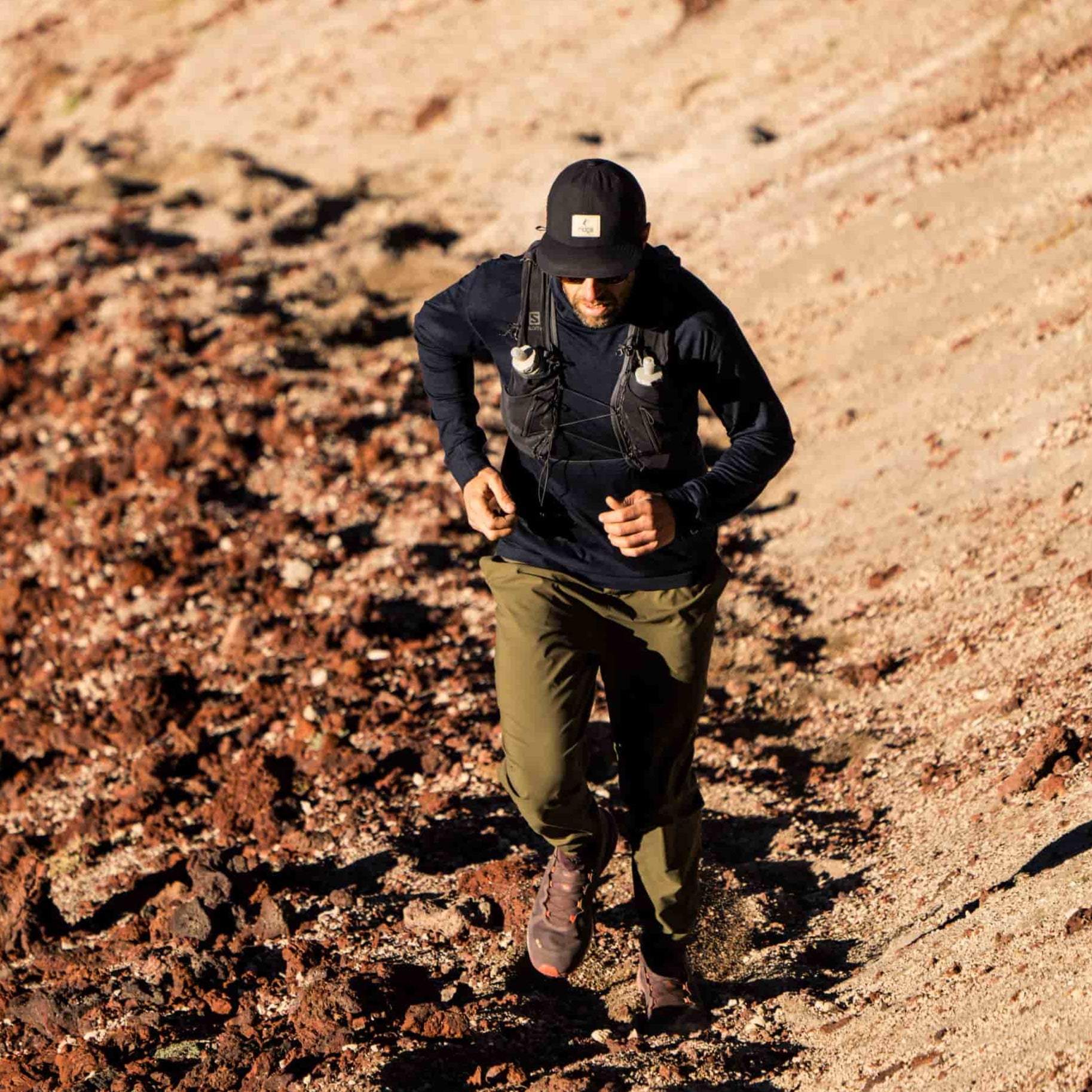 A man trail running in Mammoth Lakes wearing the Pursuit hoodie and a Ridge Merino hat