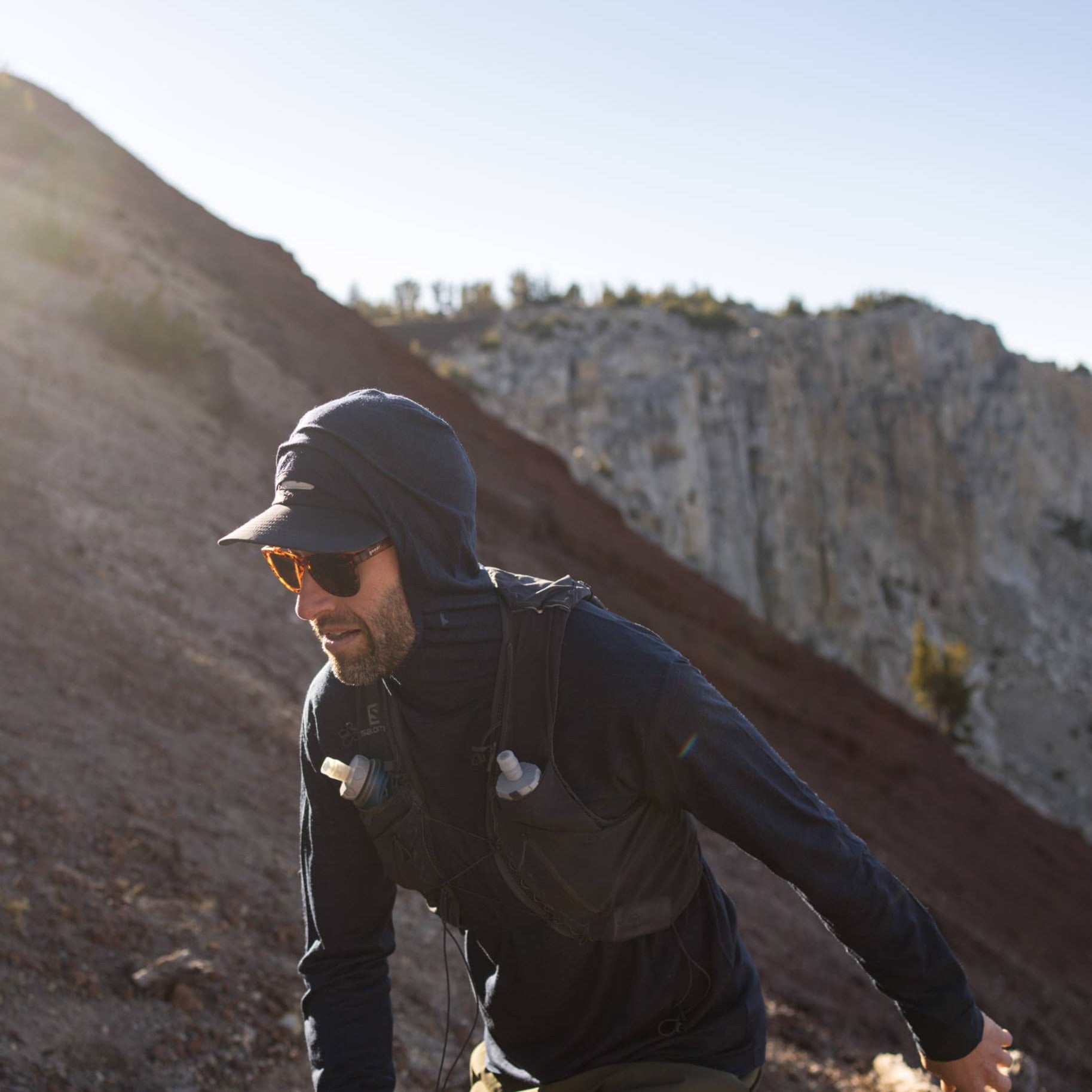 A man trail running in Mammoth Lakes wearing the Pursuit hoodie and a Ridge Merino hat
