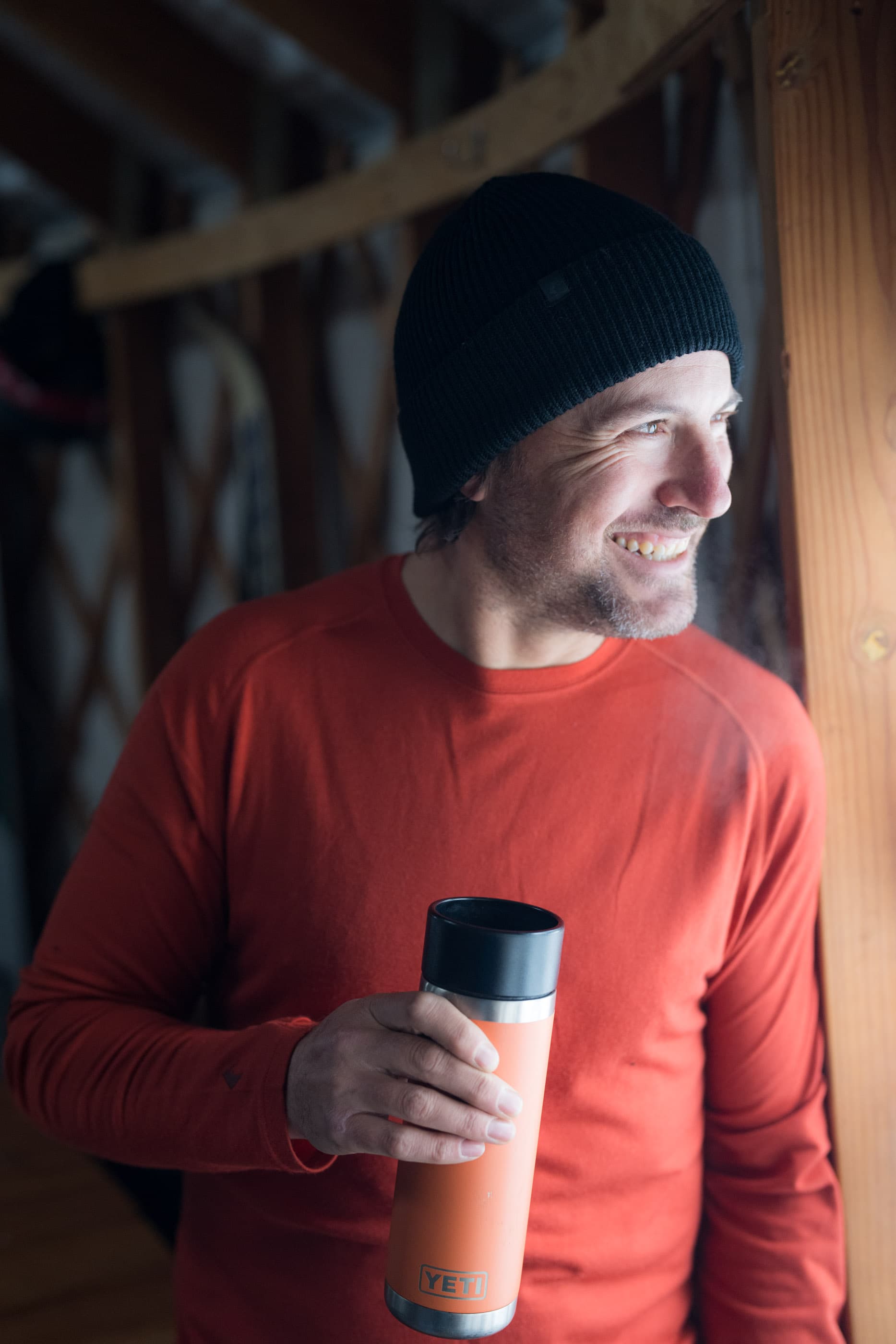 a backcountry skier looks out the window of a backcountry yurt wearing a Ridge Merino long sleeve shirt